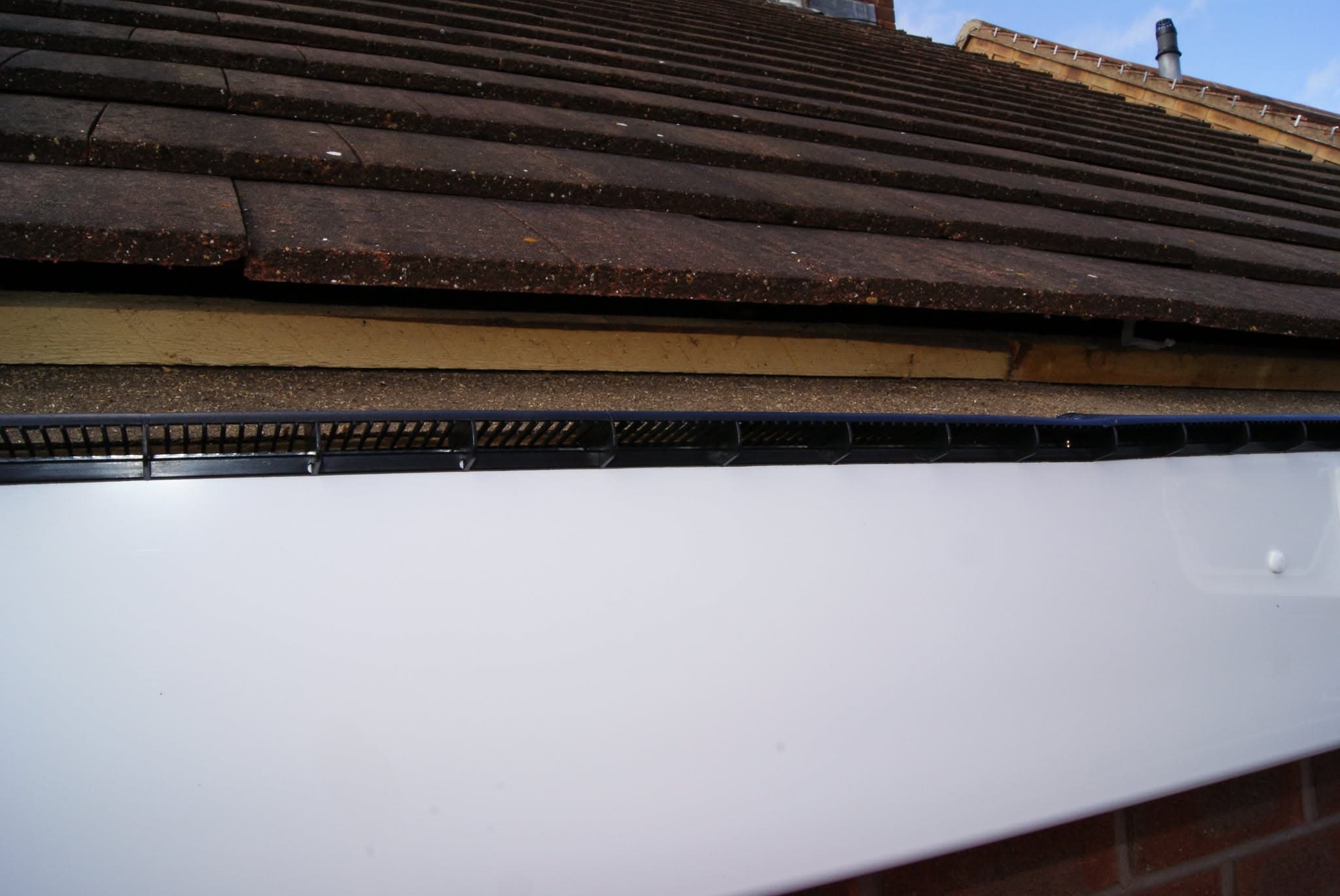 Pitched roof with dark concrete tiles, fascia board and black guttering visible
