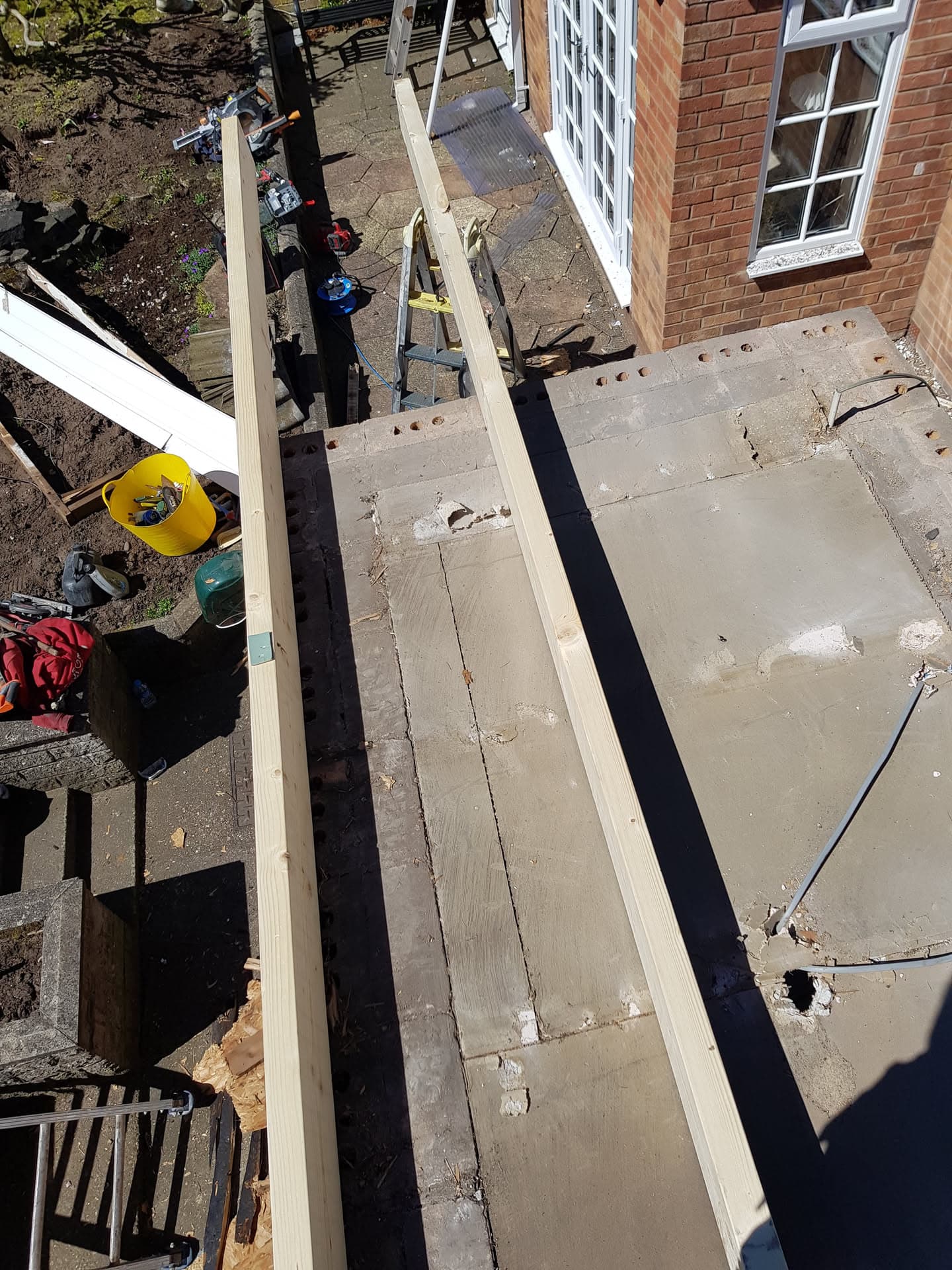 Flat roof with new white fascia boards and tools on ground below