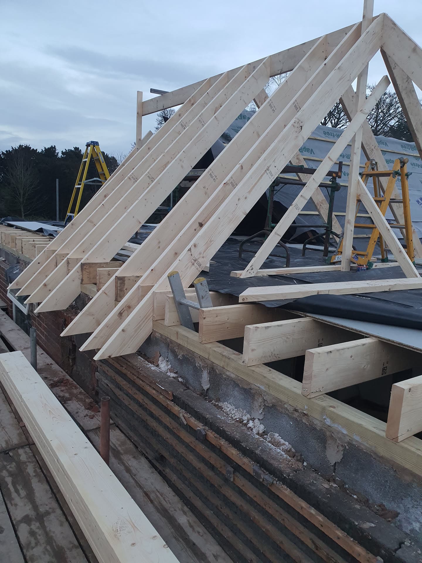 Timber roof structure under construction showing exposed rafters and joists on a pitched roof
