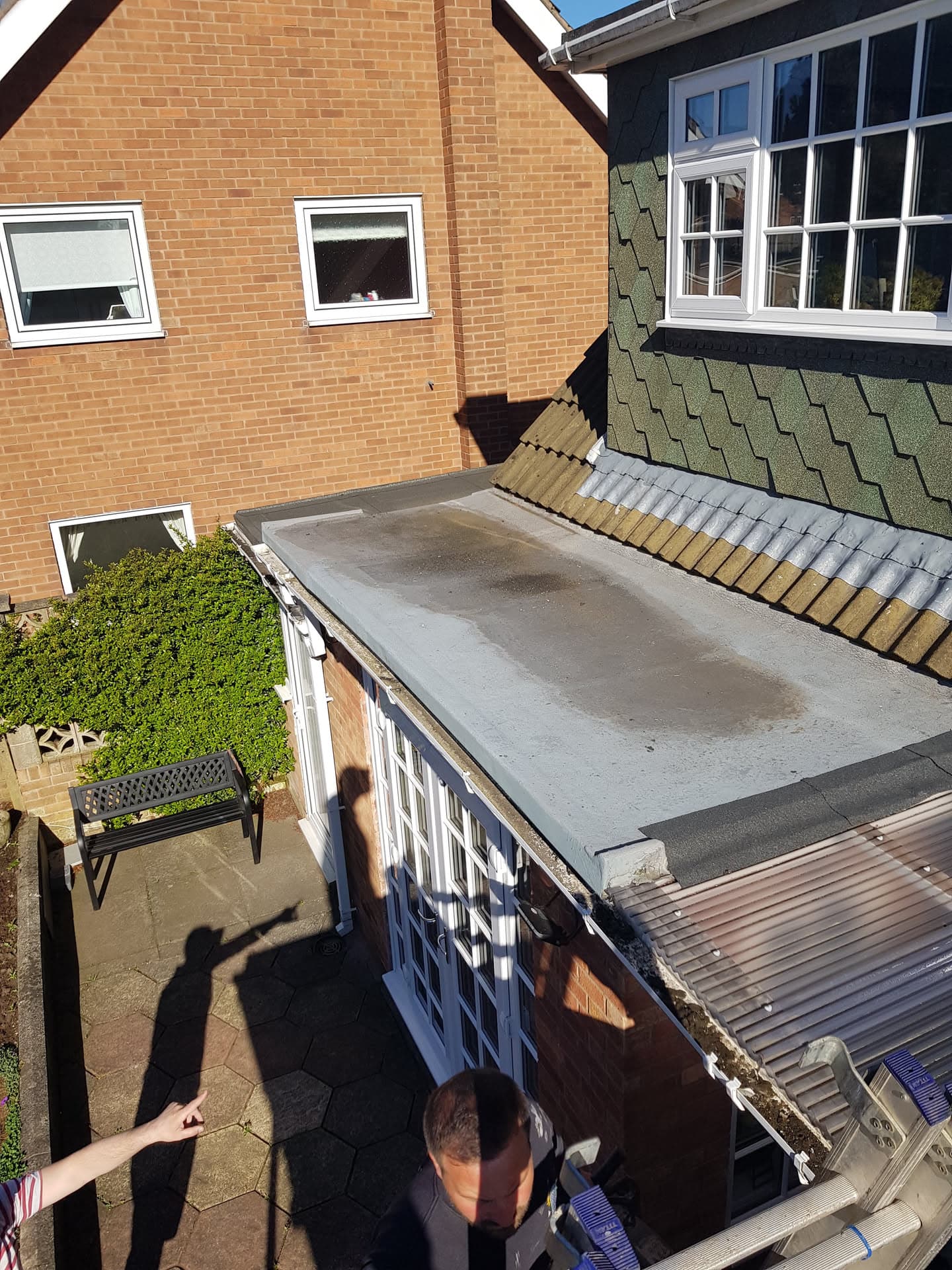 Flat roof extension with GRP fibreglass surface and white fascias, adjacent to tiled pitched roof