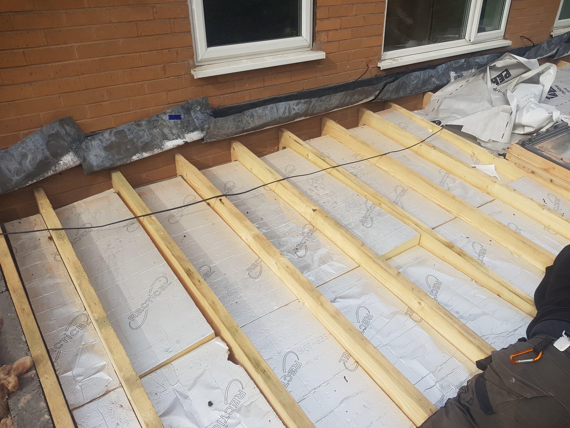 Flat roof construction with timber battens and insulation membrane being installed