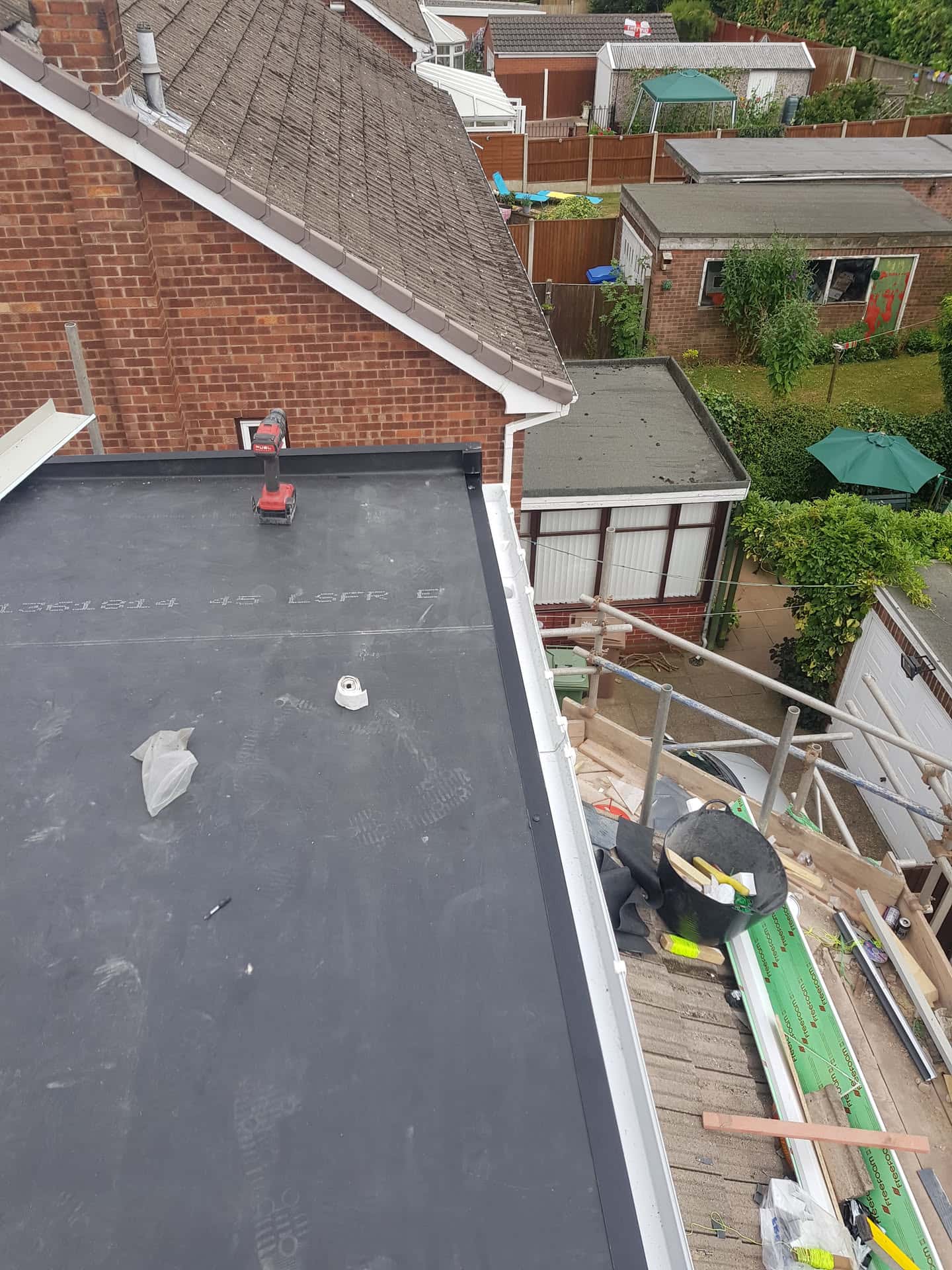 Newly installed dark grey flat roof with white fascia trim on residential extension