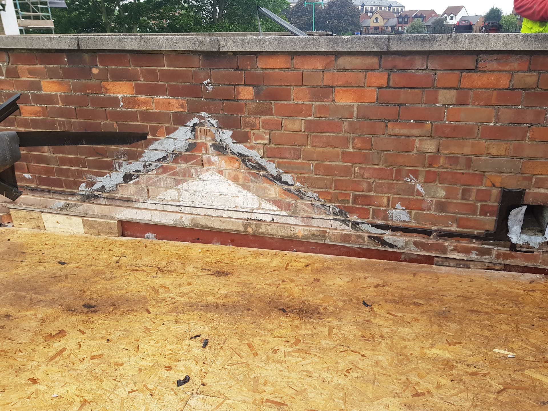 Flat roof with OSB boarding and exposed brick parapet wall with damaged lead flashing