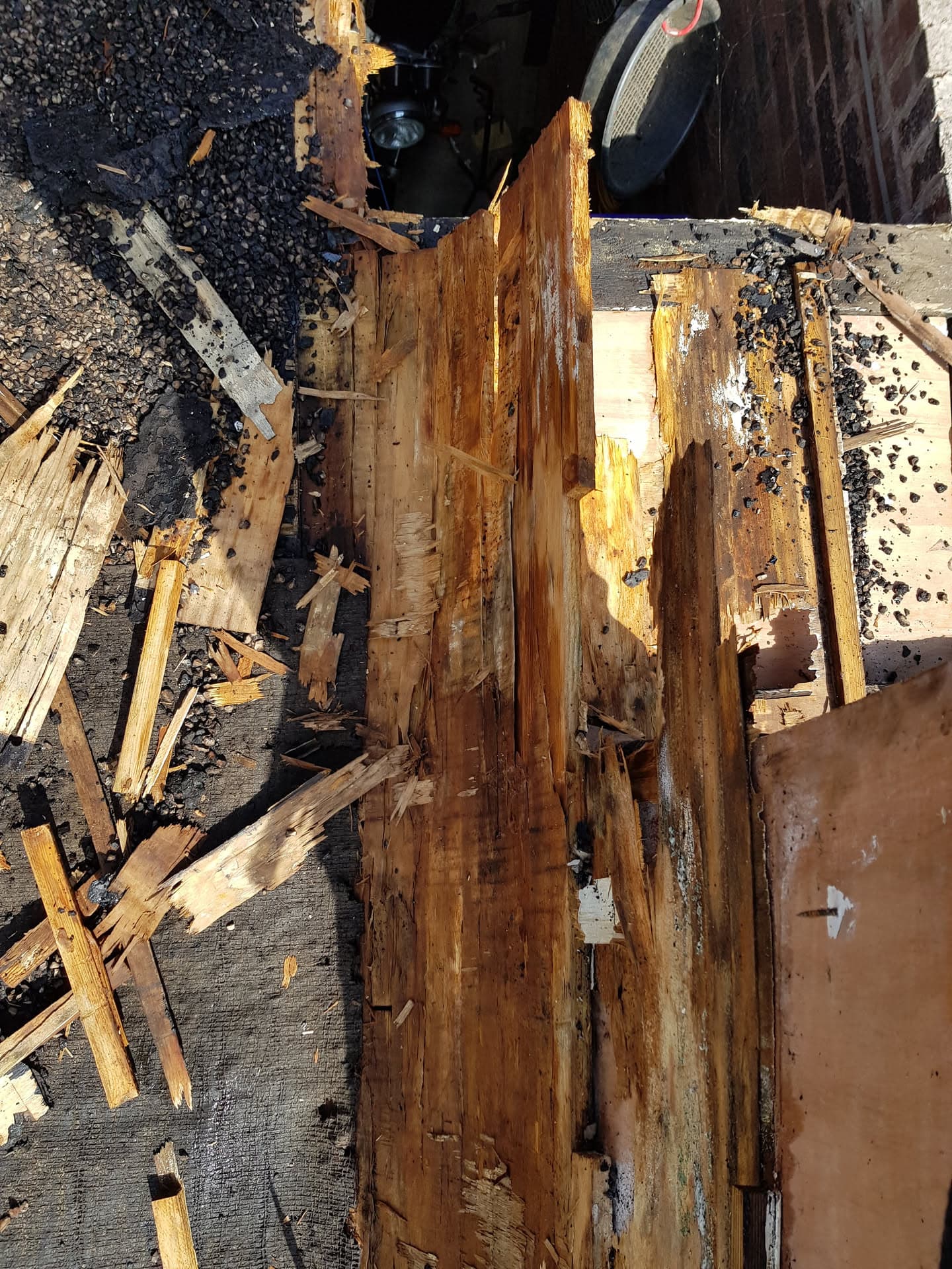 Damaged wooden fascia boards and roof decking with deteriorated felt during repair work