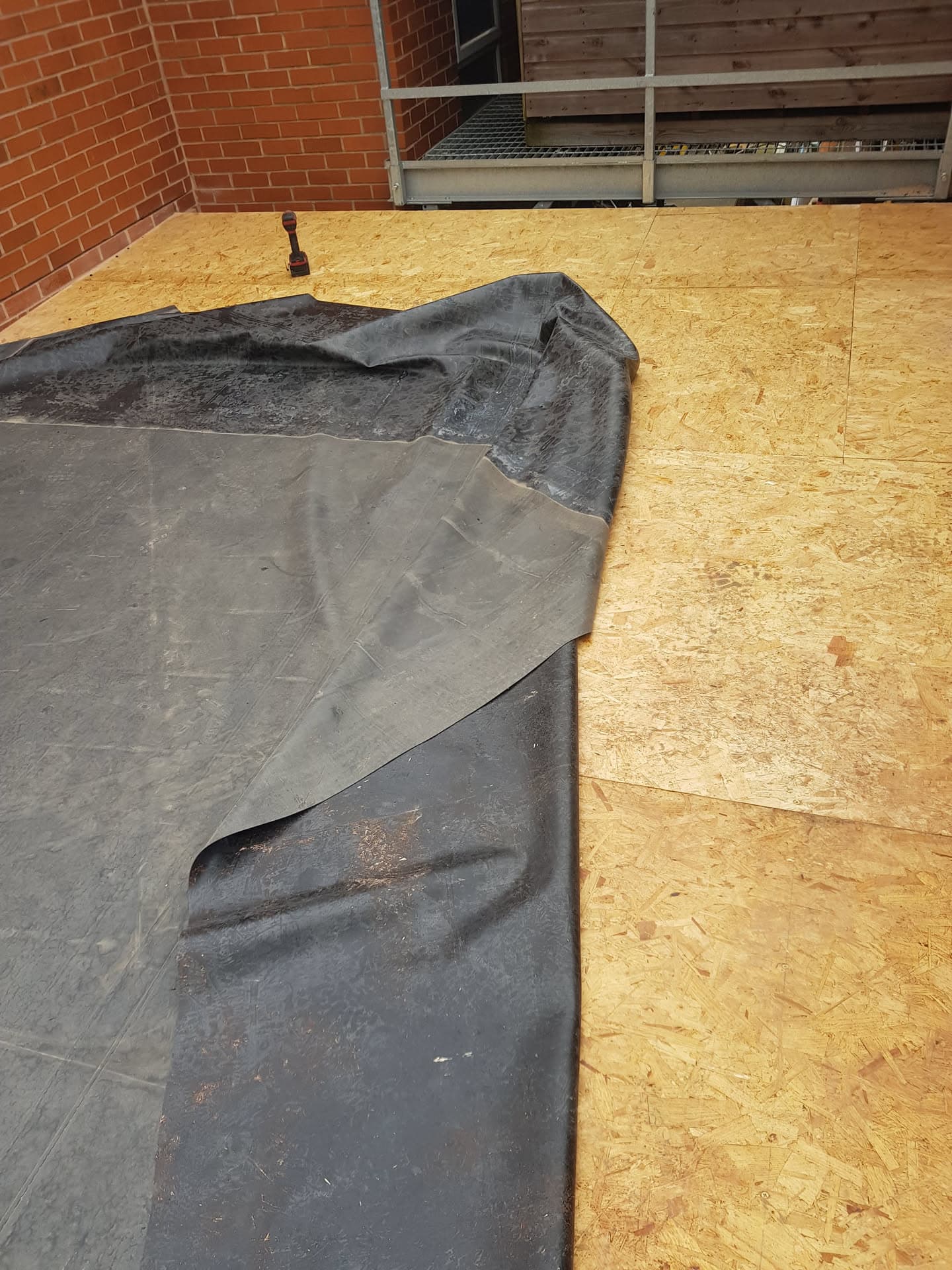 Flat roof with EPDM rubber membrane being installed on OSB decking