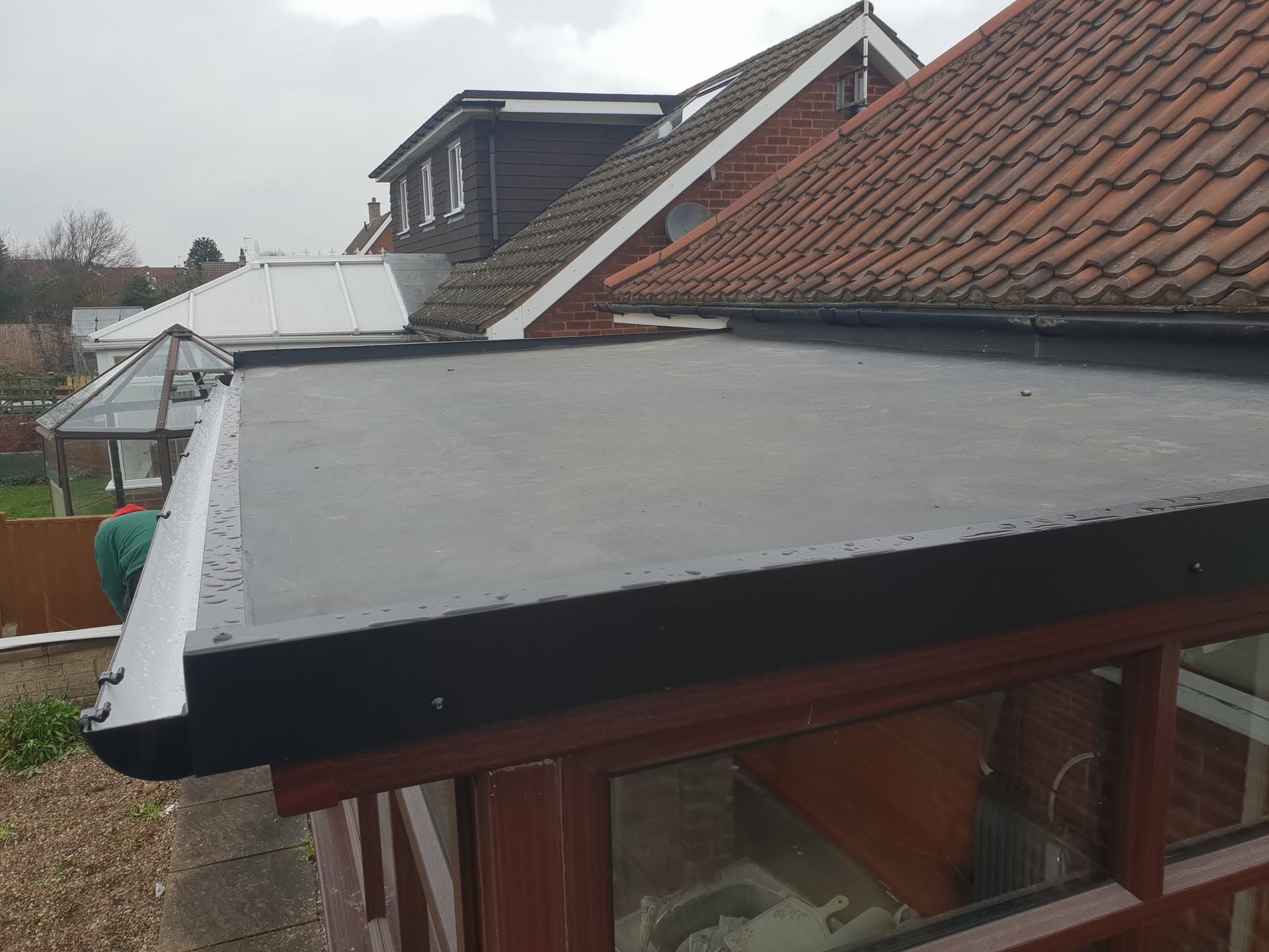 Flat roof with grey EPDM rubber membrane and white fascia trim on residential extension
