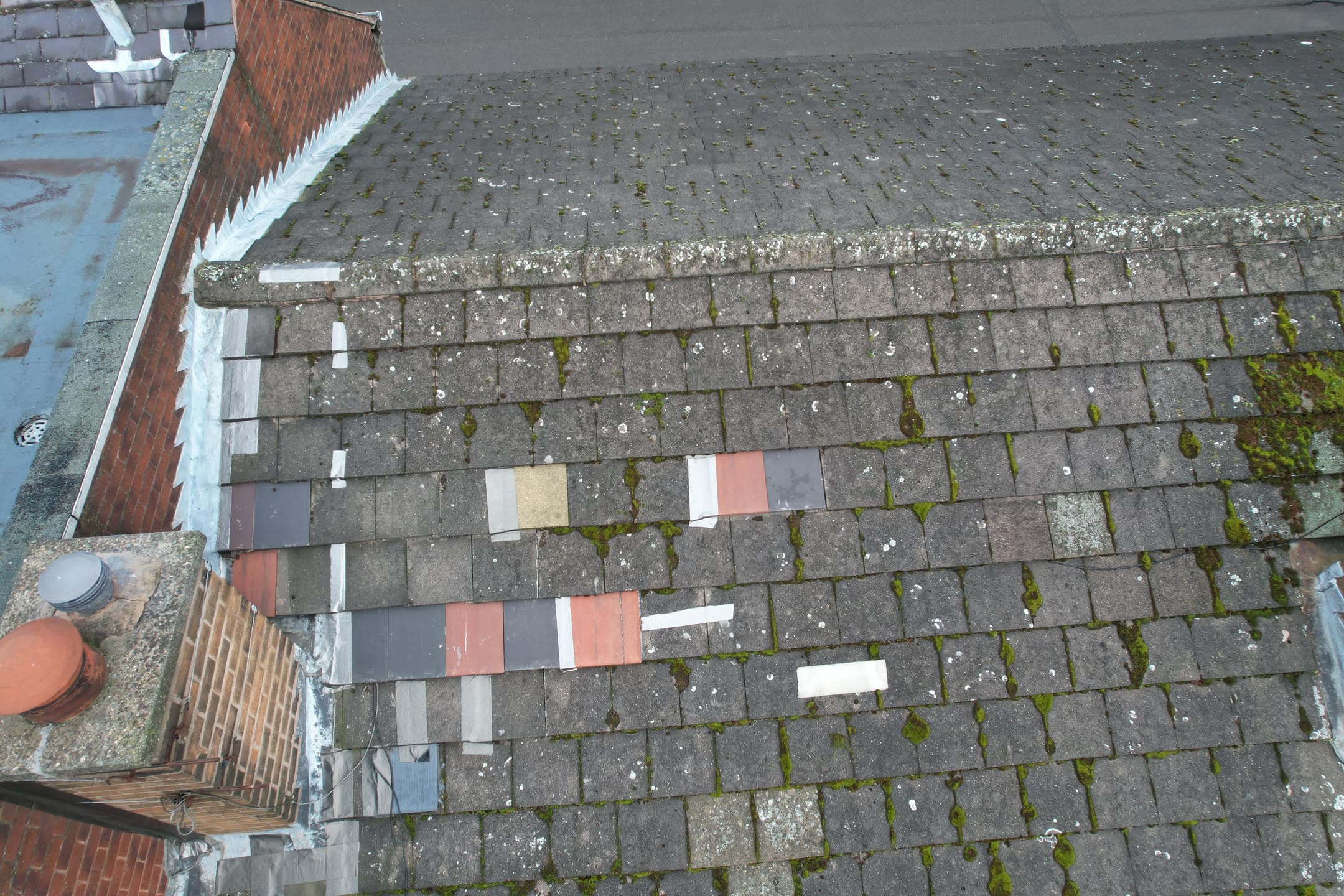 Aerial view of pitched roof with weathered concrete tiles and colour sample tiles laid out