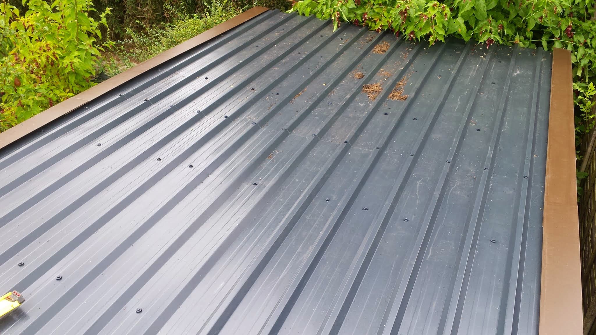 Grey corrugated metal roof with visible fixings and timber trim