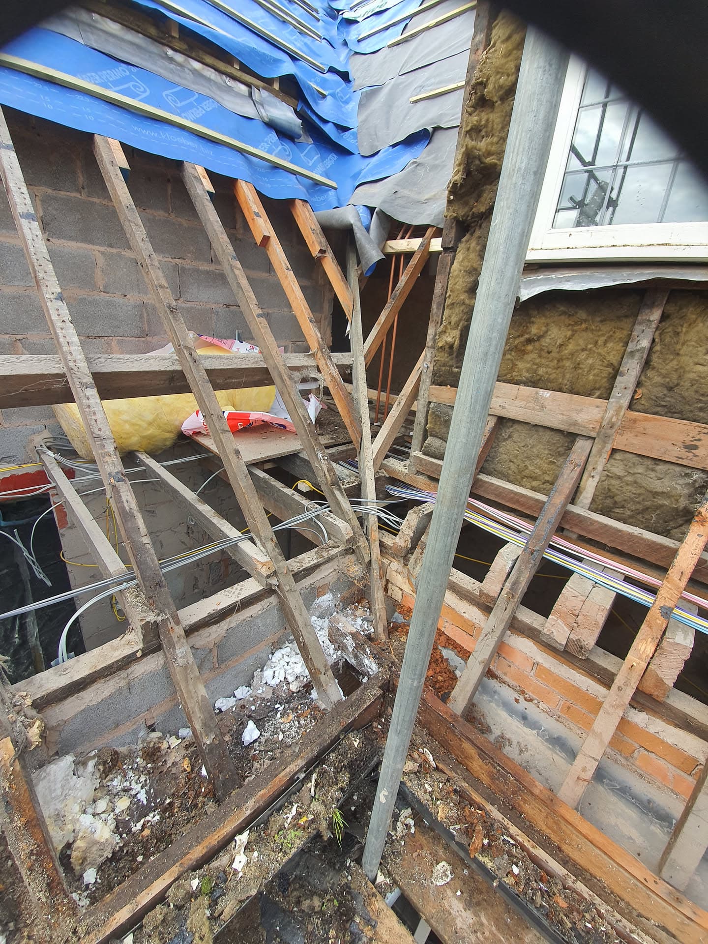 Pitched roof stripped back to timber rafters and battens with blue membrane and exposed insulation during renovation