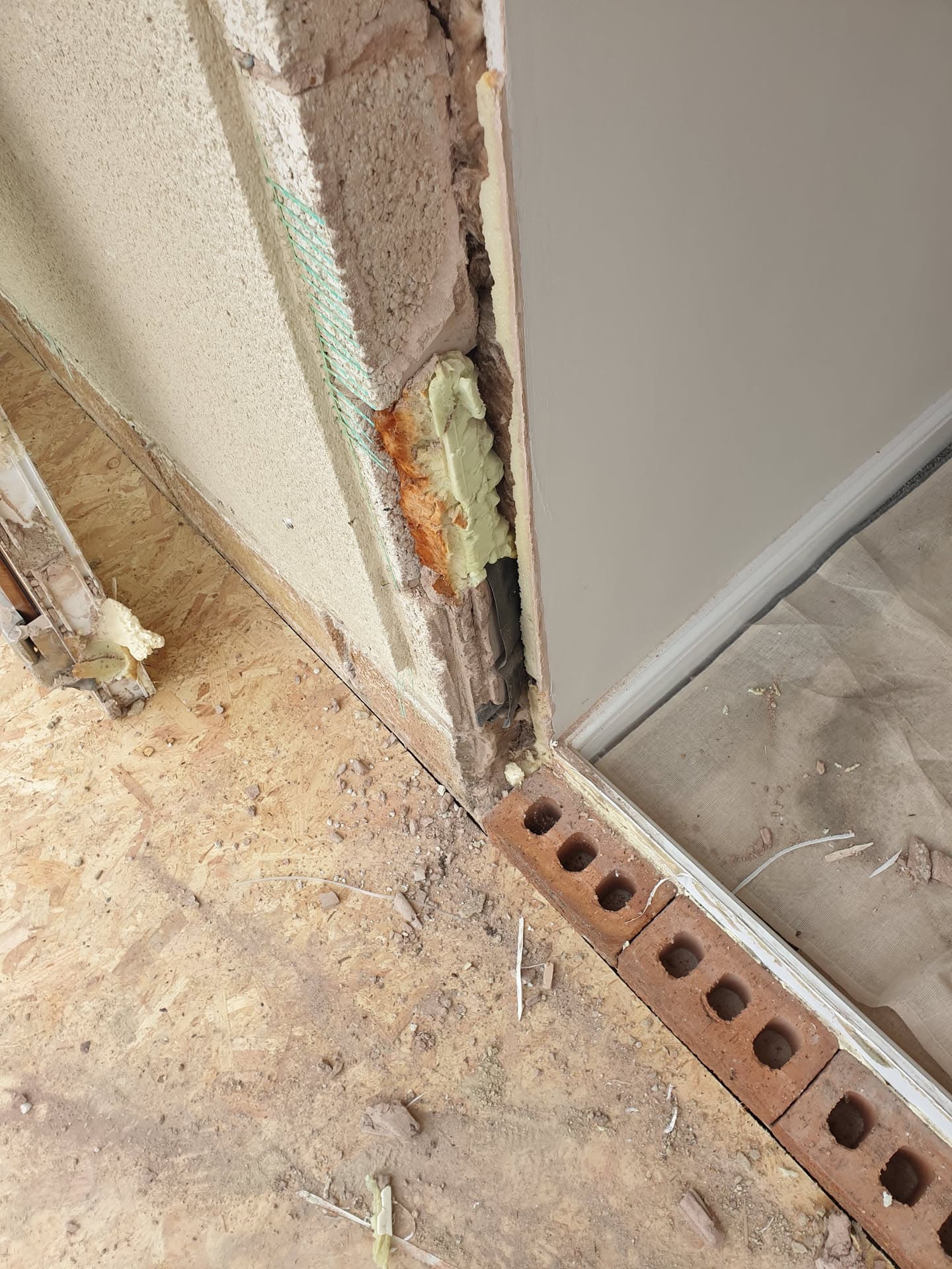 Damaged wall cavity showing exposed insulation and deteriorated brickwork during renovation work