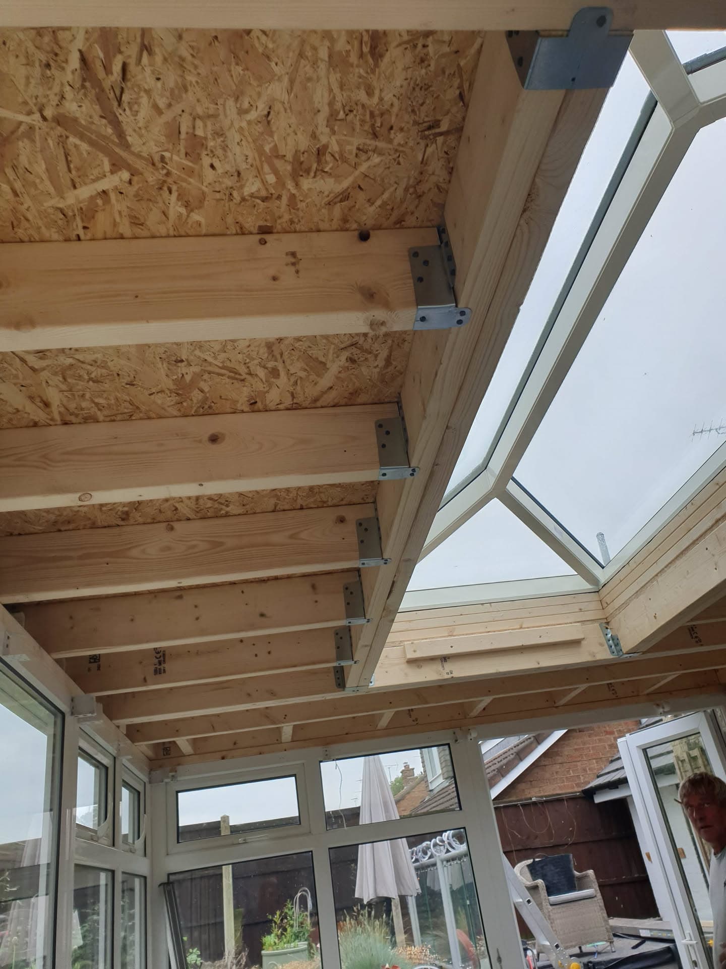 Interior view of conservatory roof construction with exposed timber beams and roof window