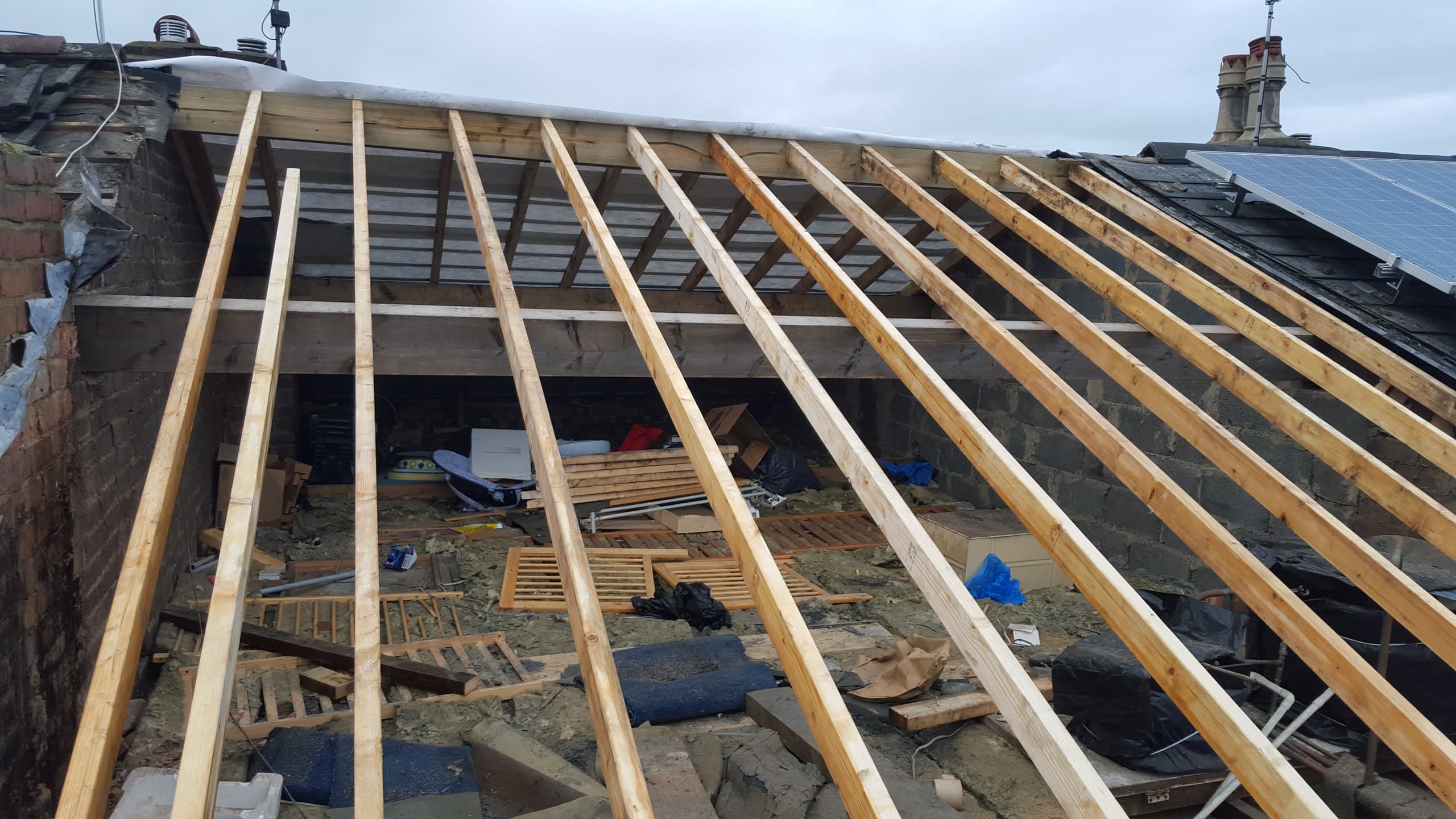 Pitched roof under construction with exposed timber rafters and battens before tiling