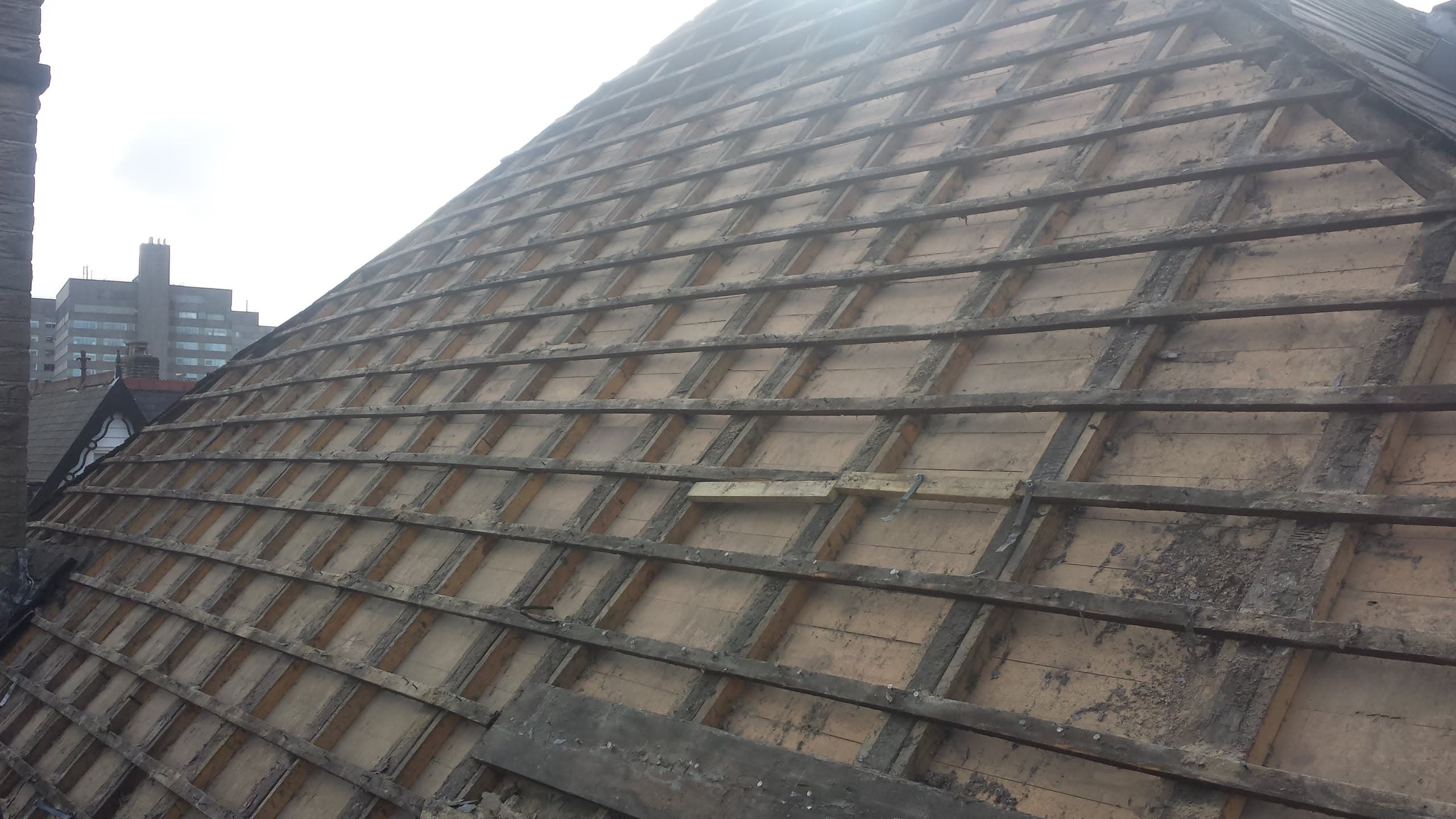 Pitched roof with tiles removed showing timber battens and roof structure