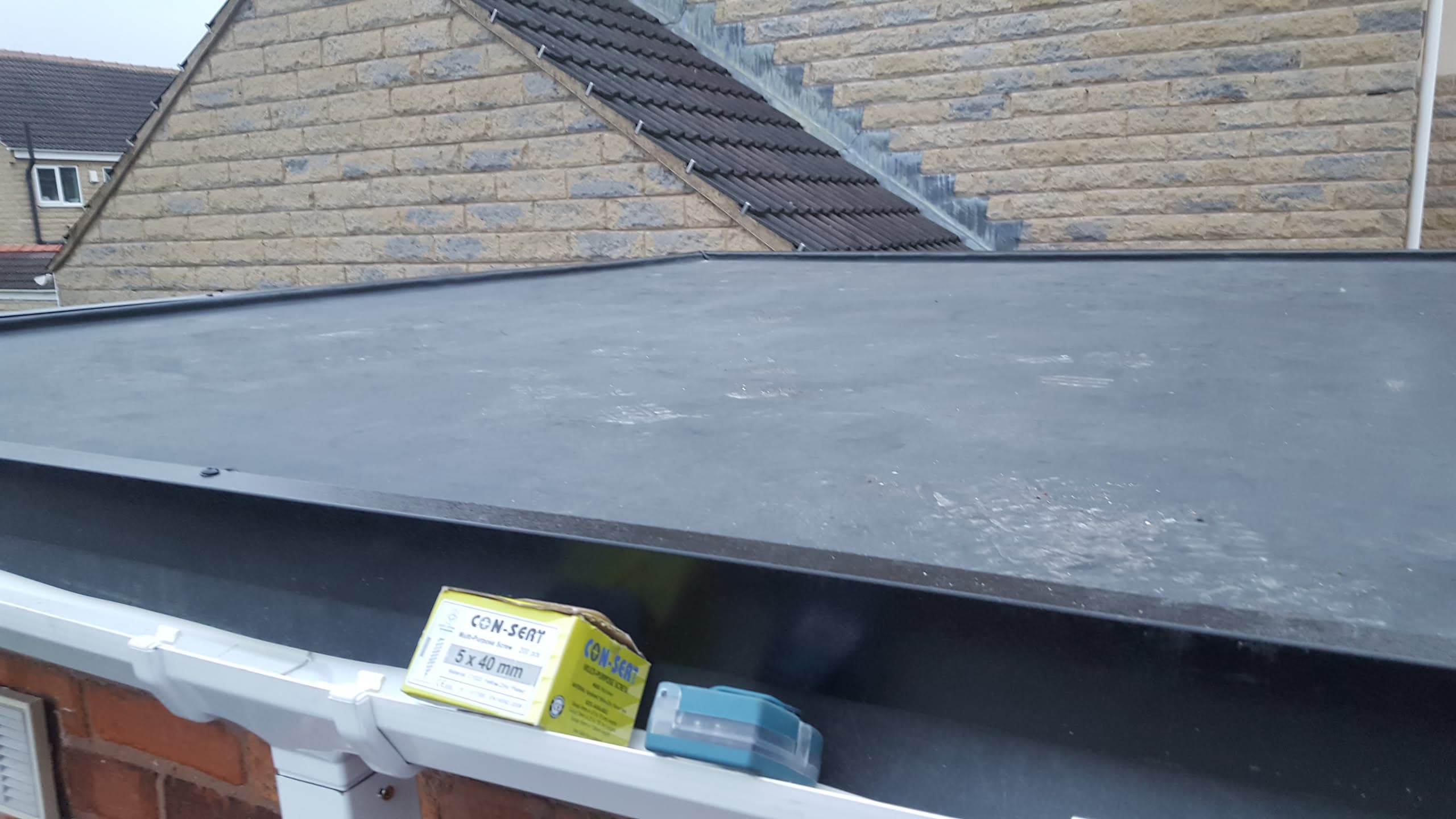 Flat roof with grey EPDM rubber membrane and white fascia board