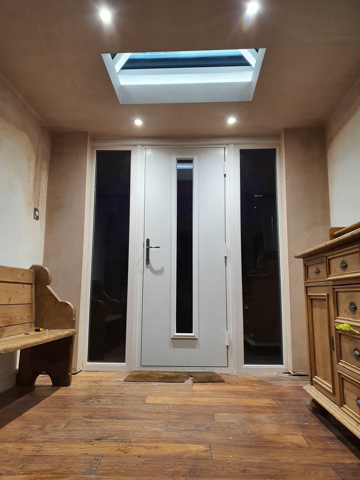 Flat roof skylight with white frame installed above entrance hallway