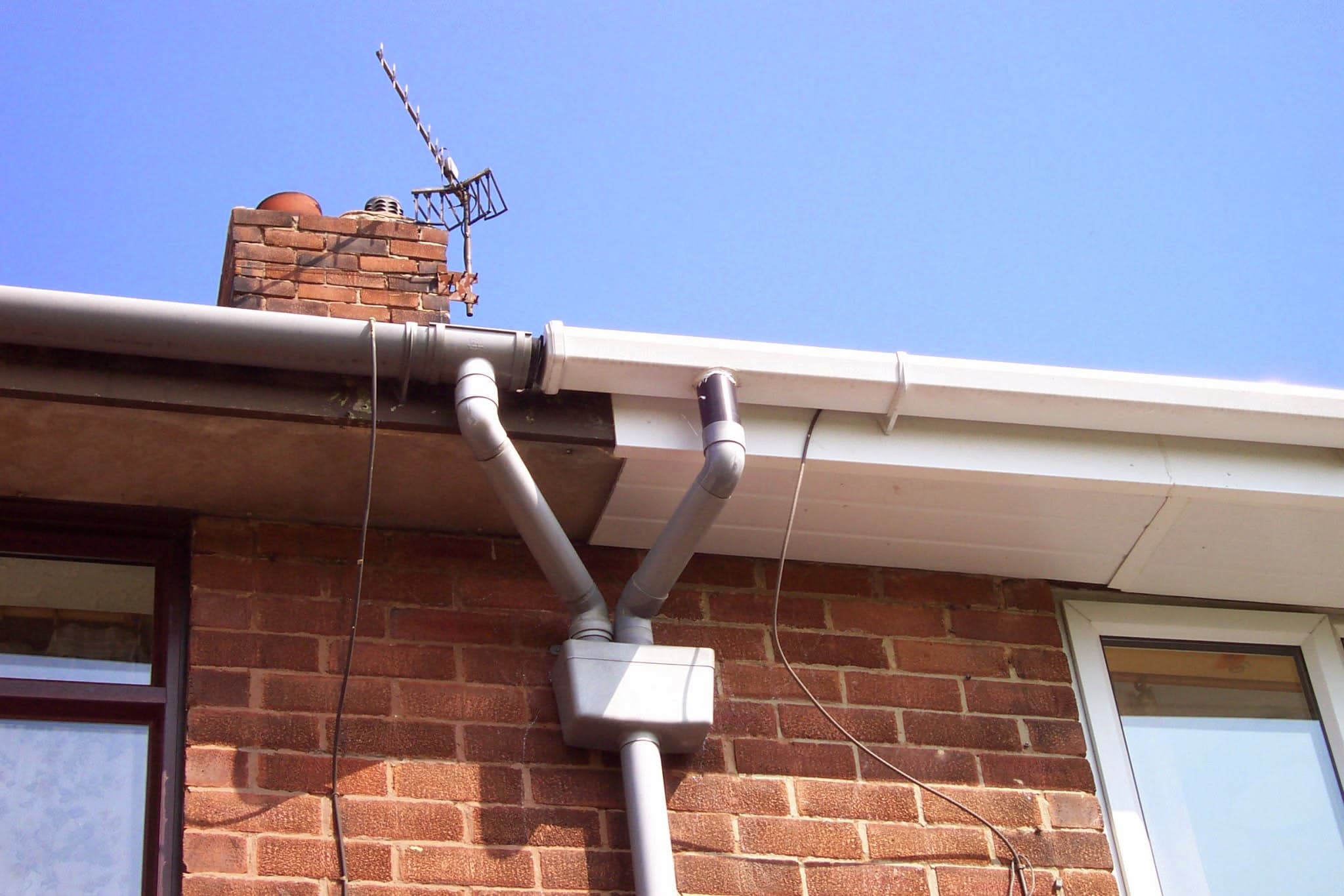 White fascia board and guttering system installed on brick house with chimney stack