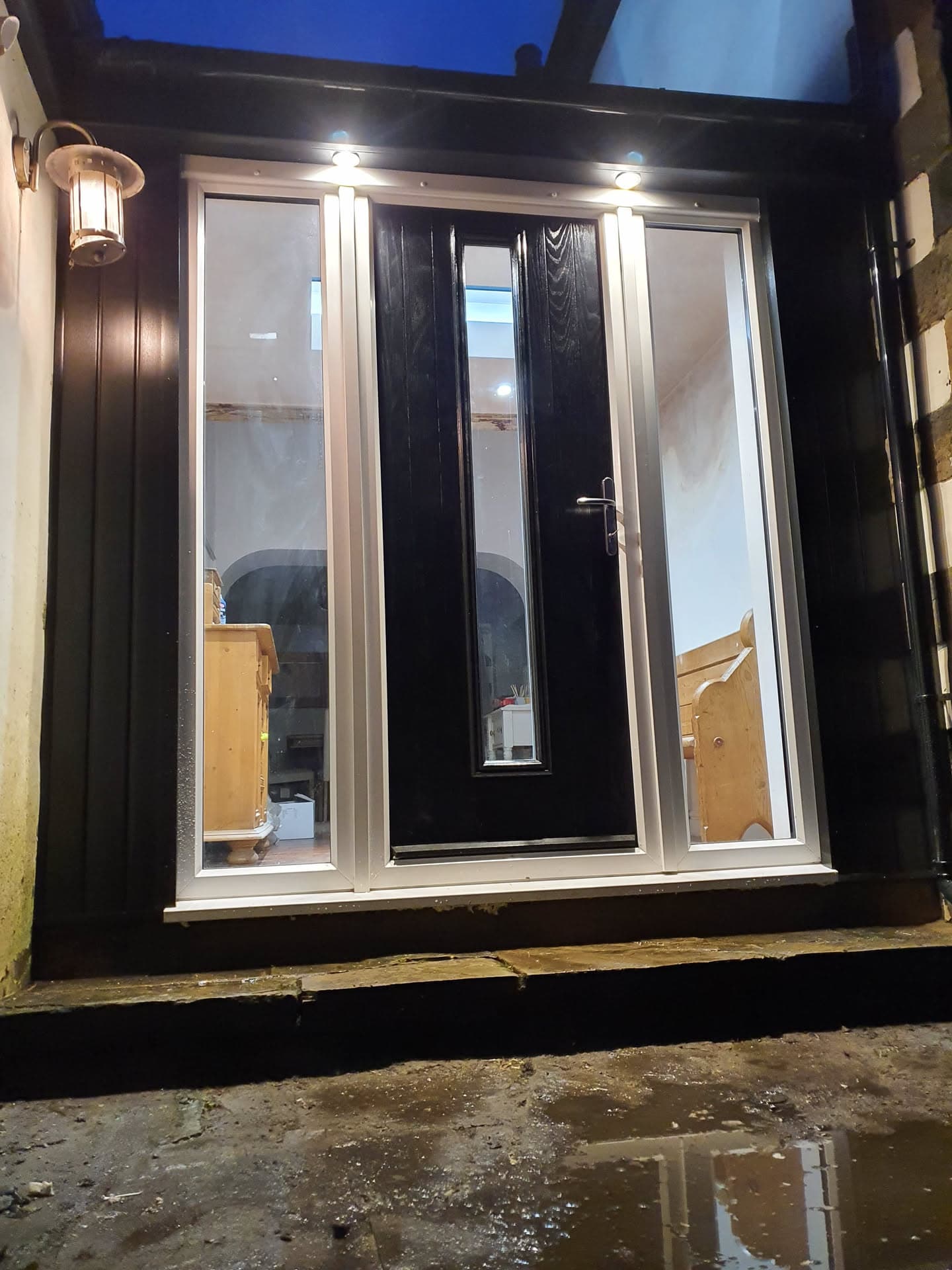 Black composite front door with glass panels and dark fascias on residential property
