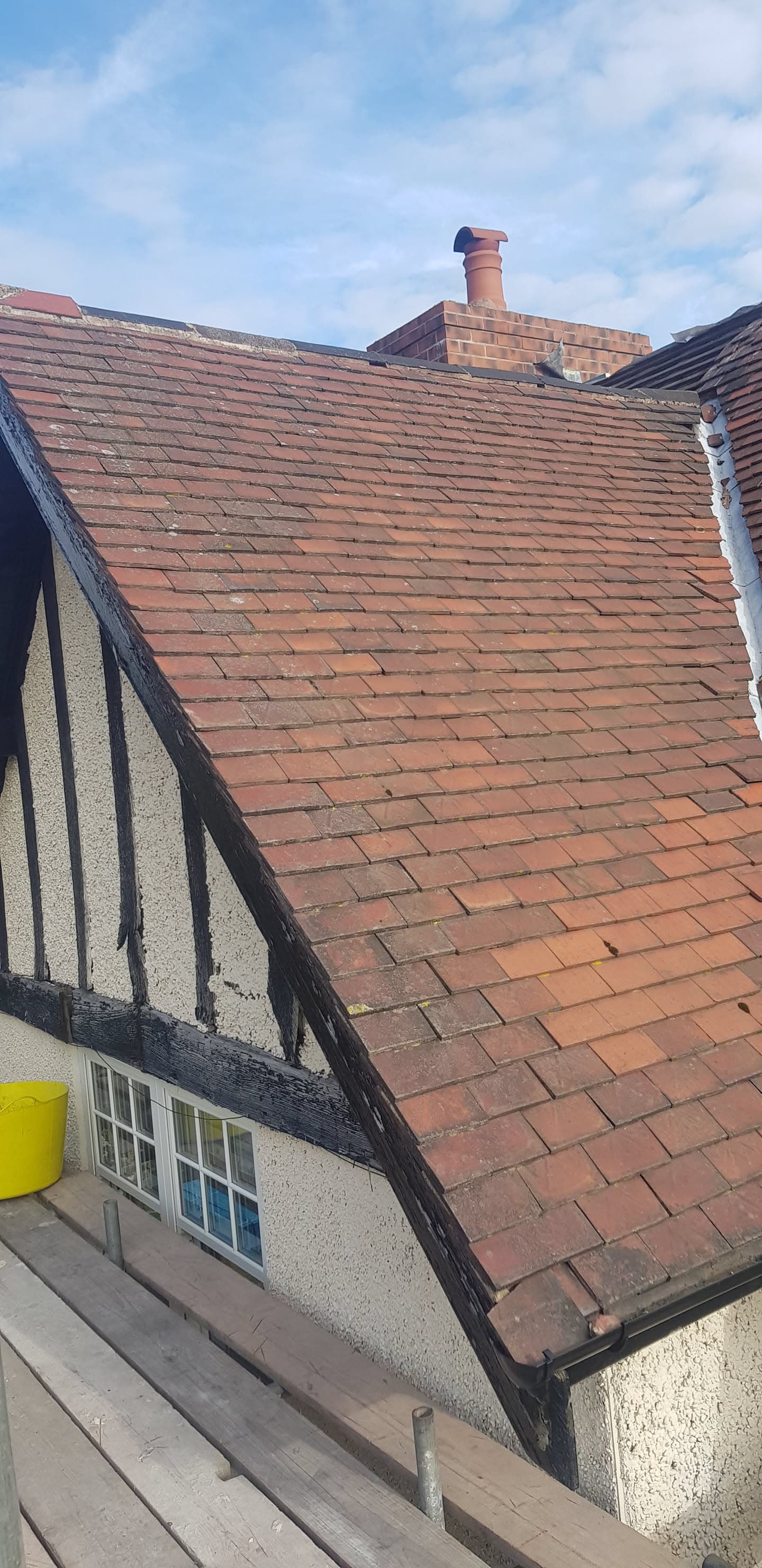 Pitched roof with terracotta clay tiles and brick chimney stack on residential property