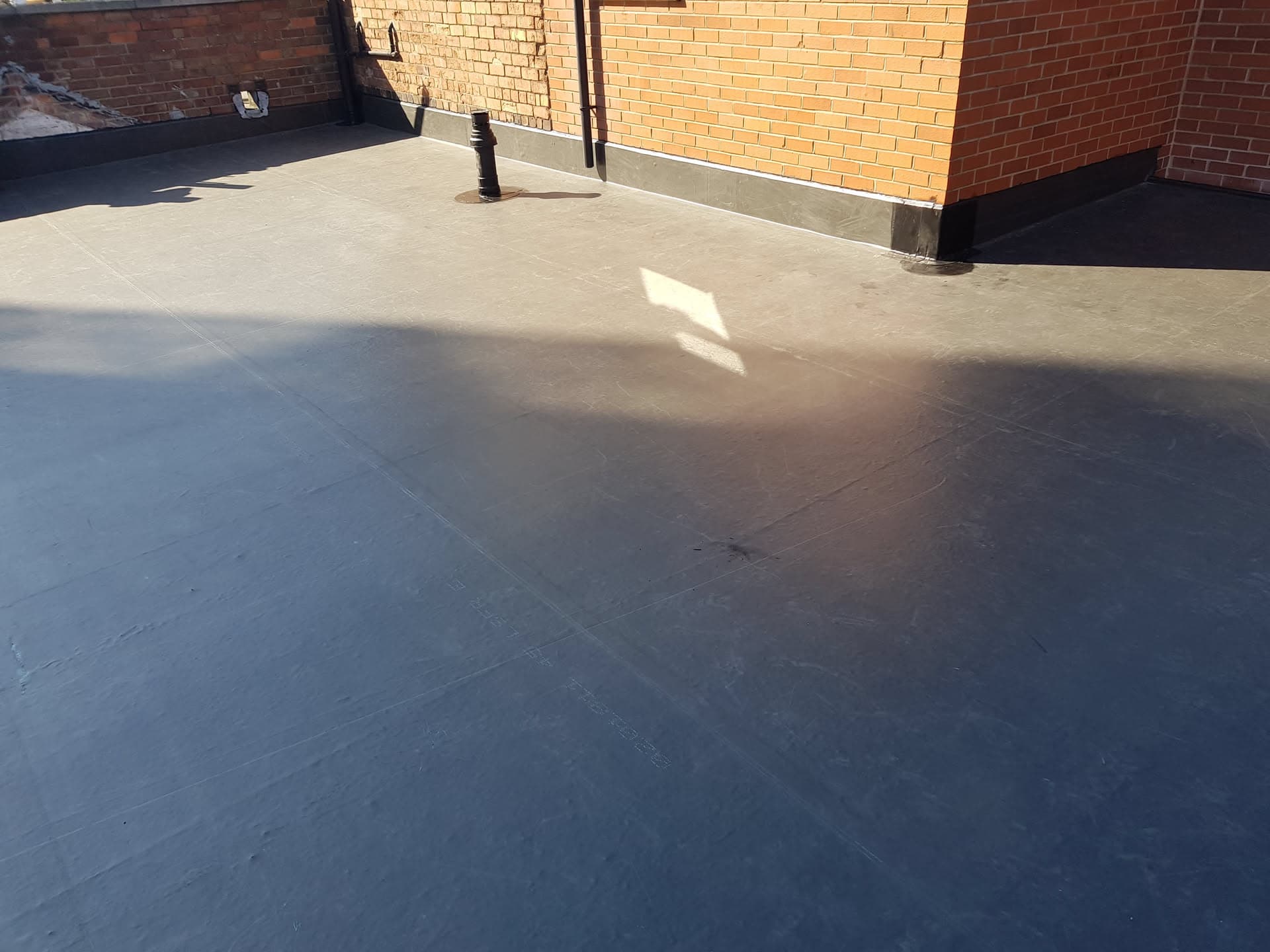 Completed flat roof installation with grey GRP fibreglass surface and vent pipe