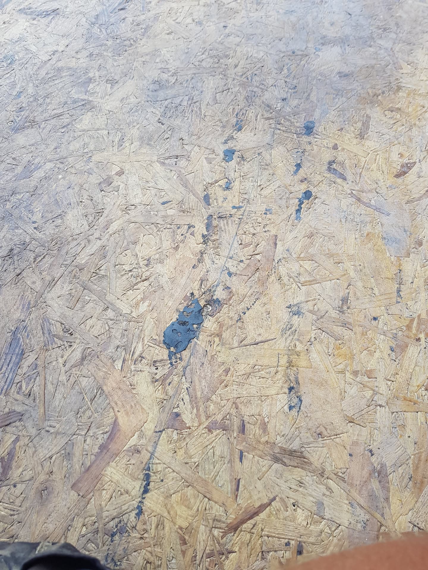 OSB board decking surface with blue adhesive marks during flat roof preparation