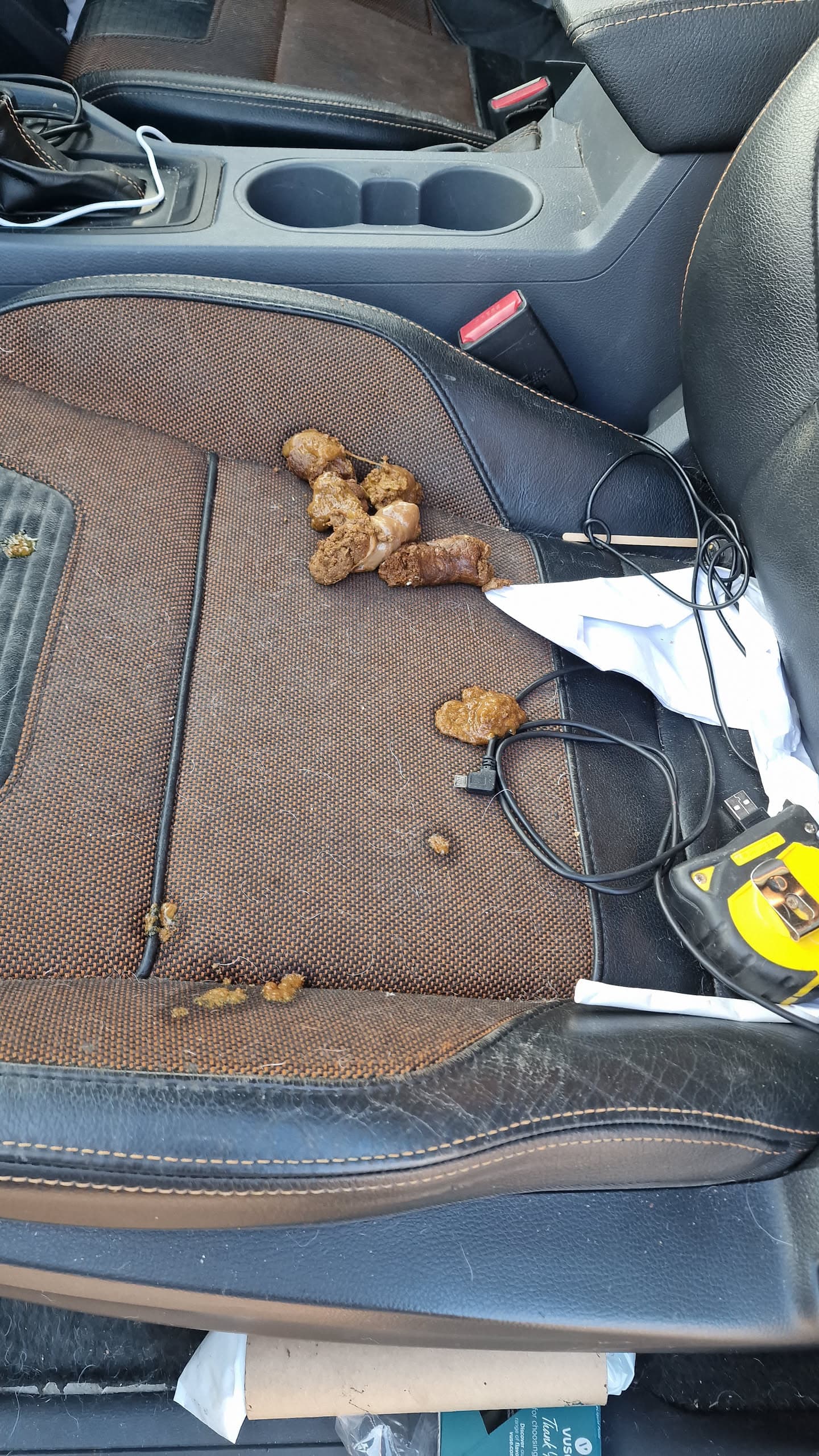 Interior of a work vehicle with muddy boots and equipment on the passenger seat