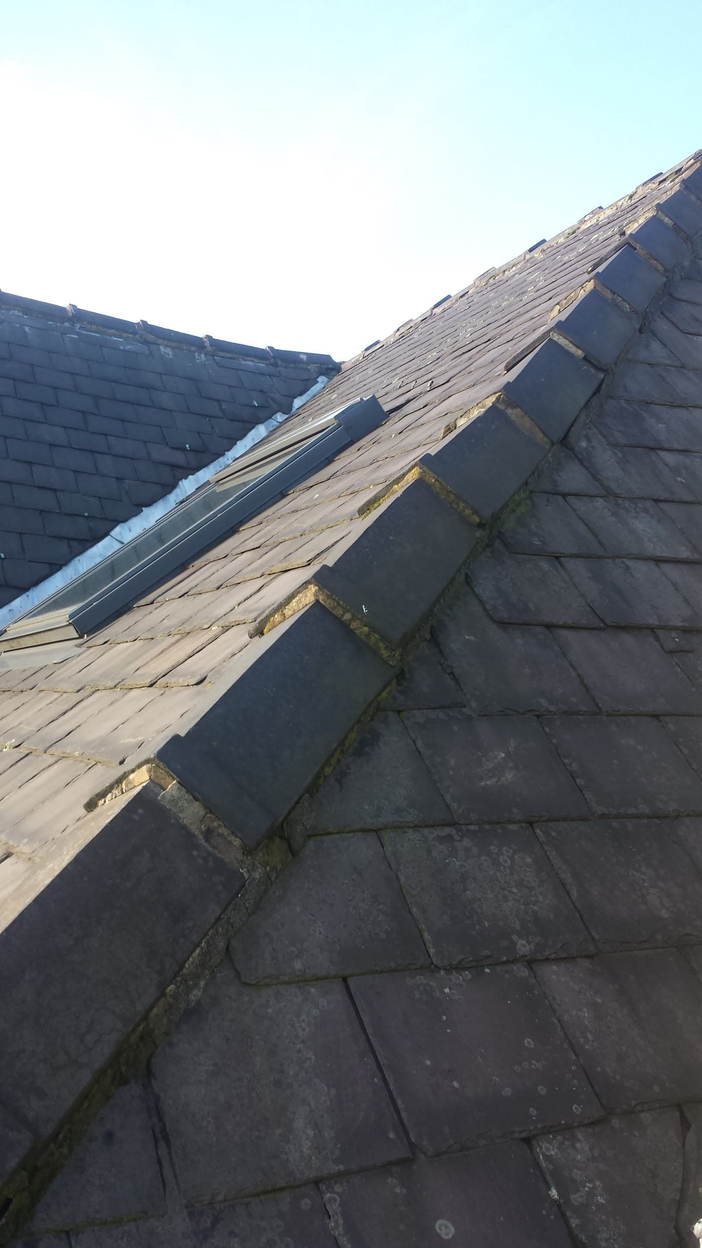 Pitched roof with grey slate tiles and exposed timber battens during re-roofing work