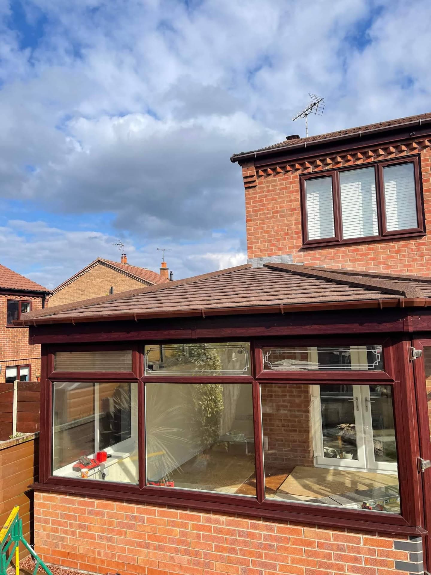 Brown tiled conservatory roof with burgundy uPVC frames and fascias