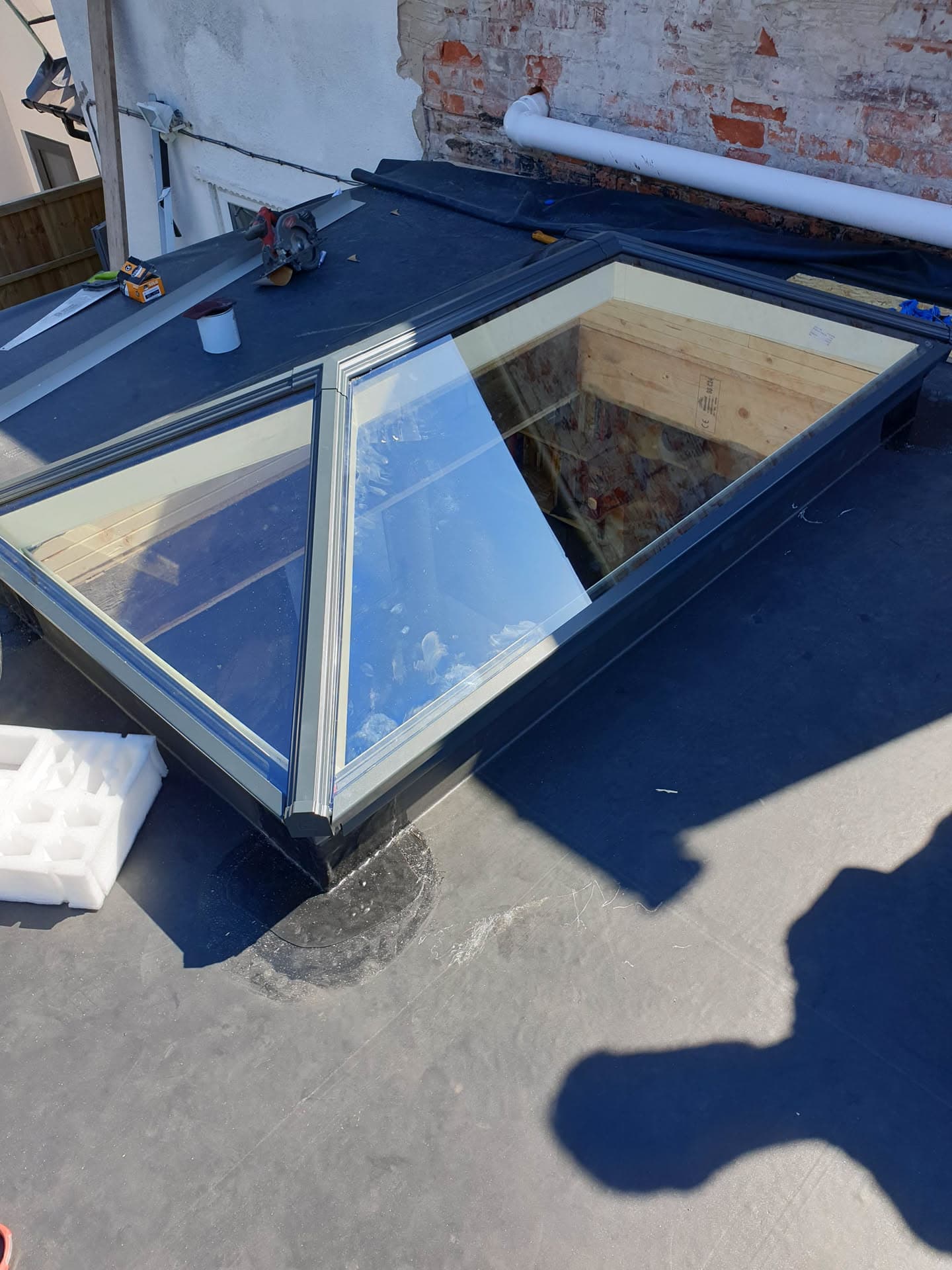 Flat roof with anthracite metal trim and glazed roof lantern under construction