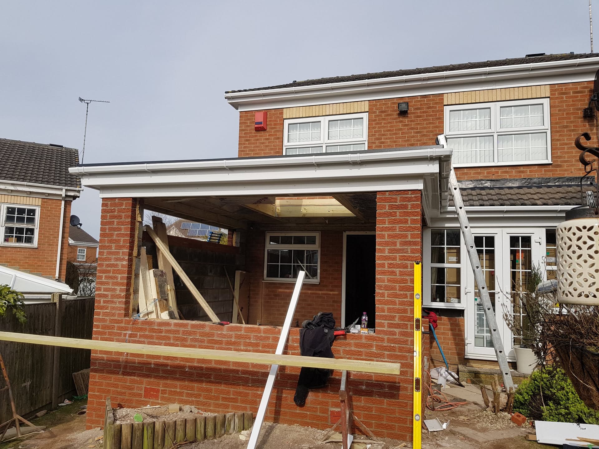 Flat roof installation on brick house extension with white fascias and guttering