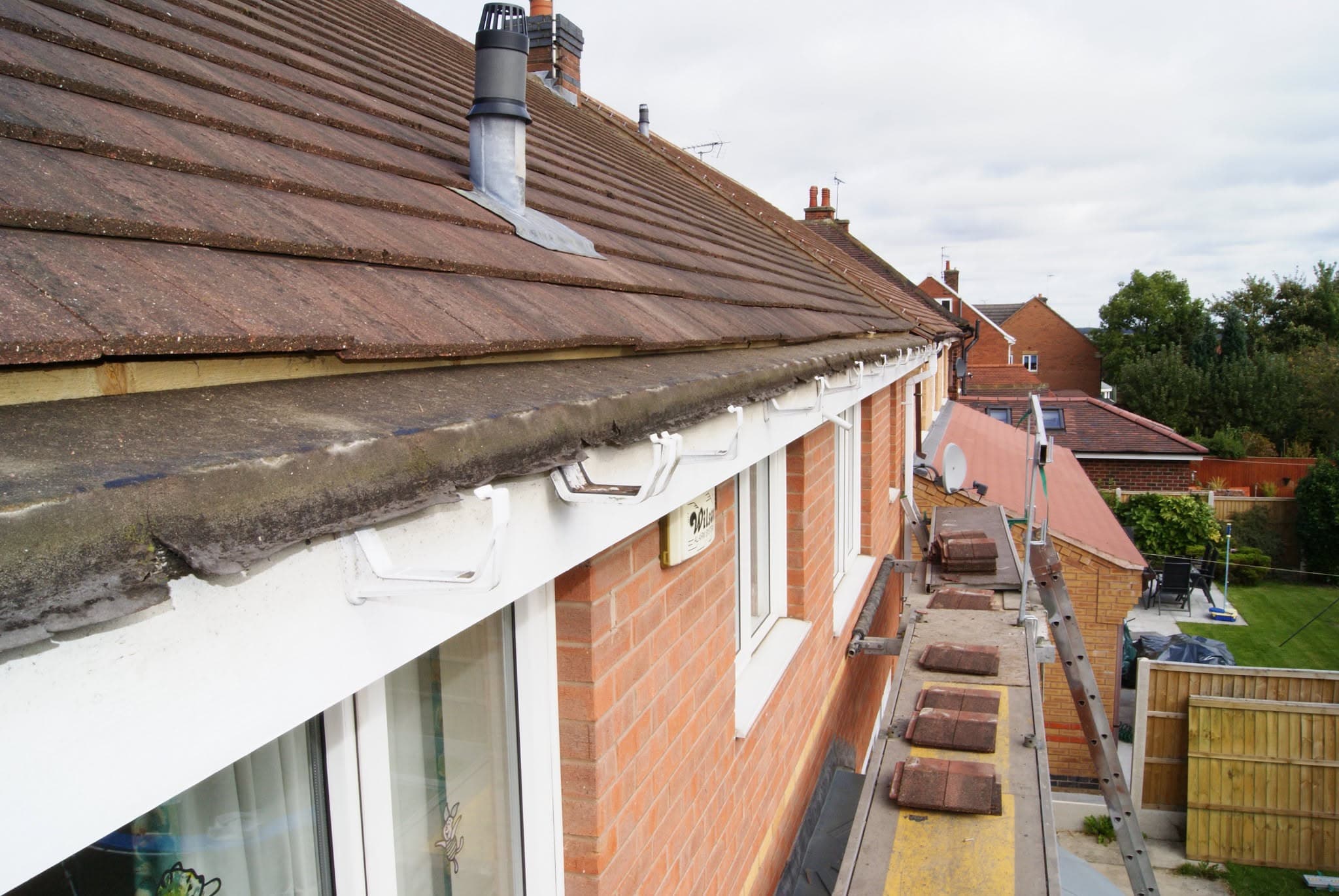 Pitched concrete tiled roof with white fascias and guttering on residential property