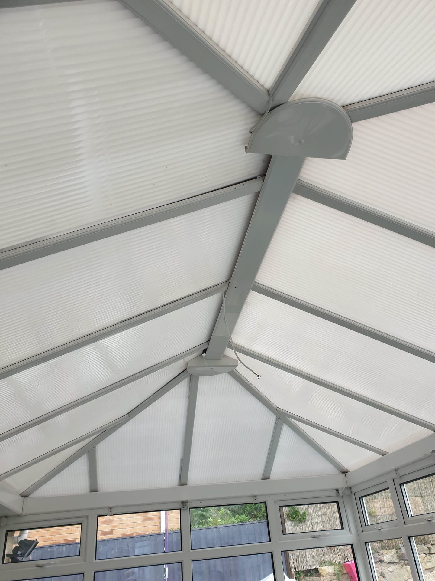 Interior view of conservatory roof with white polycarbonate panels and grey aluminium framework