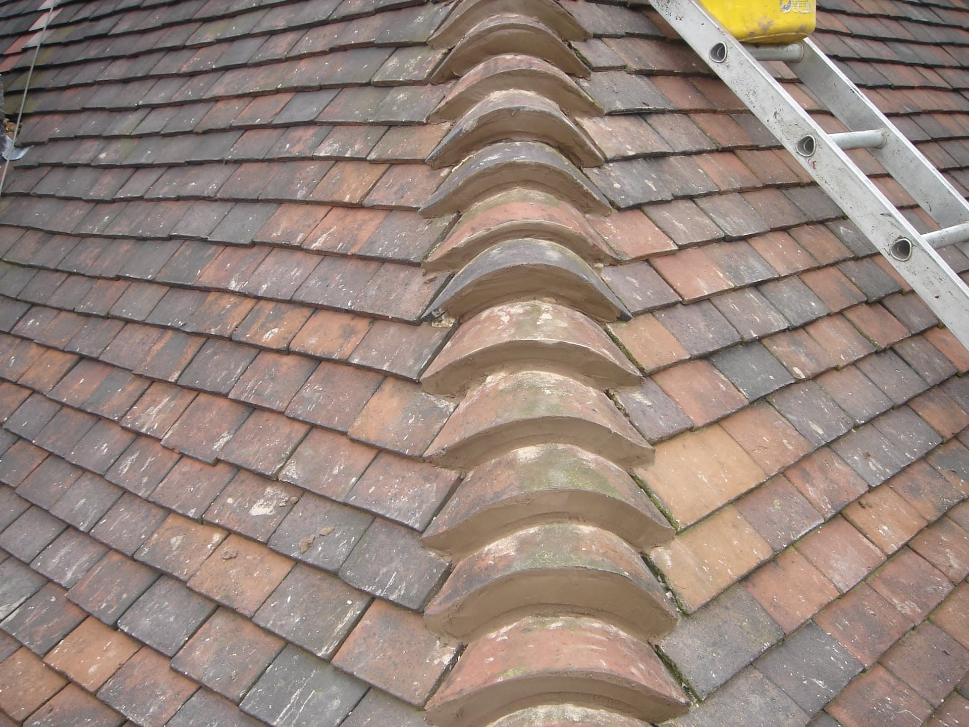 Pitched roof with mixed terracotta and grey concrete tiles and rounded ridge tiles