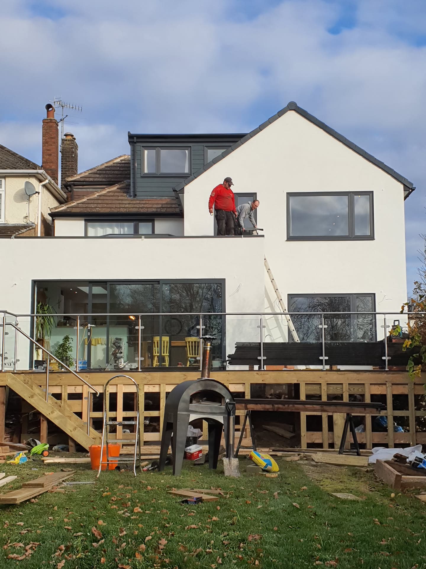 Fitters working on pitched tiled roof with dark grey dormer extension on white rendered house