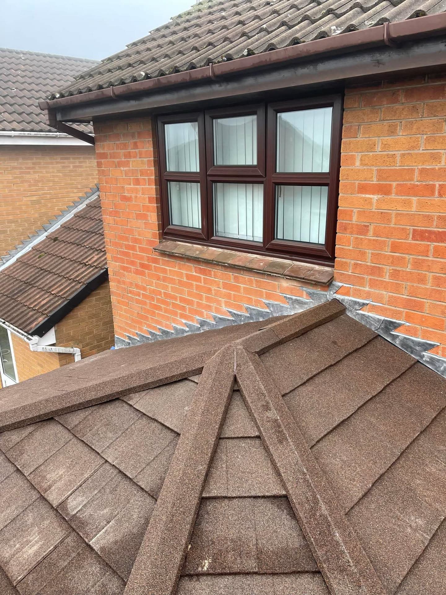 Brown concrete tiled pitched roof with dormer window, fascias and guttering