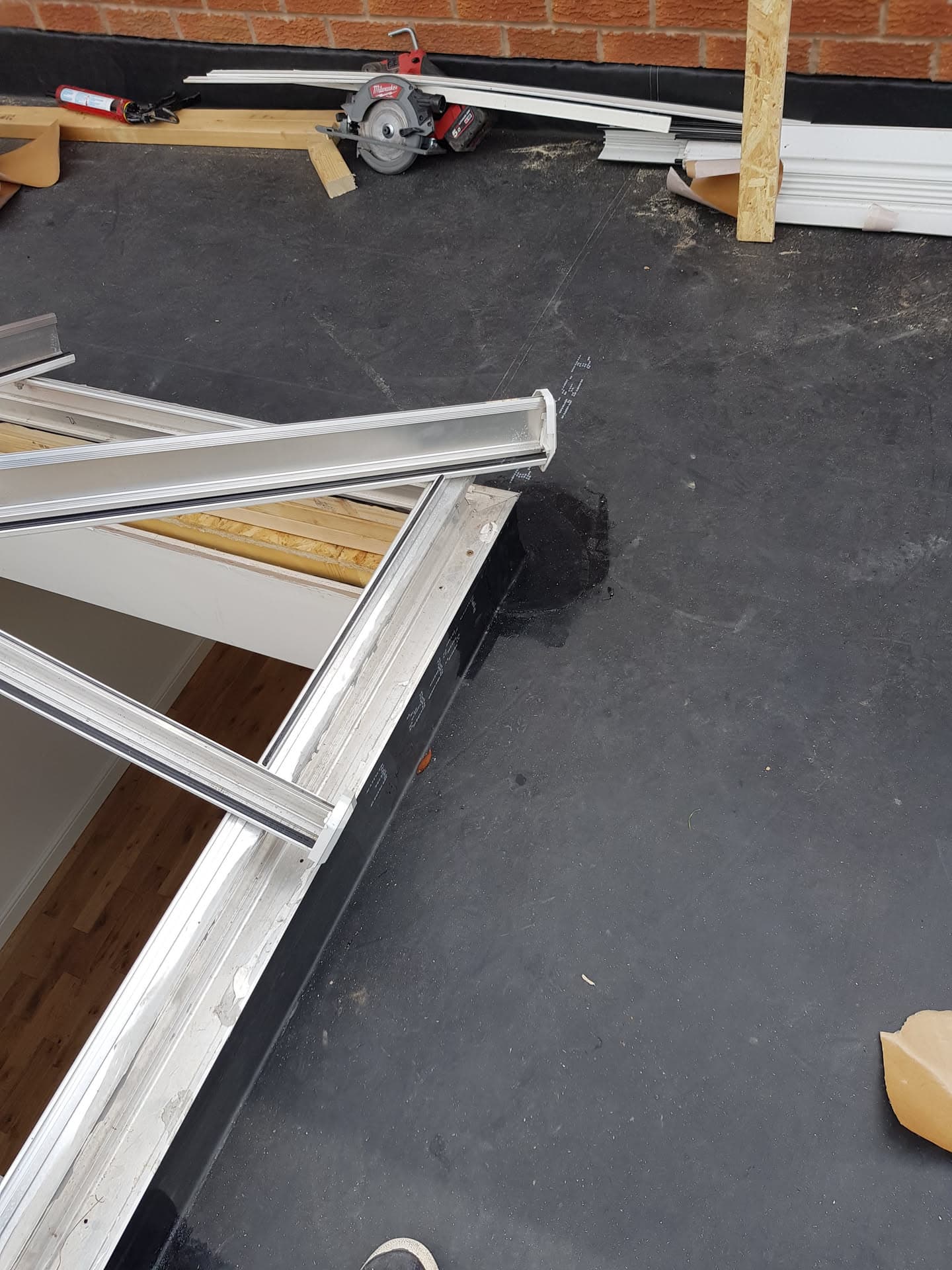 Flat roof with black felt covering and white fascia boards during installation