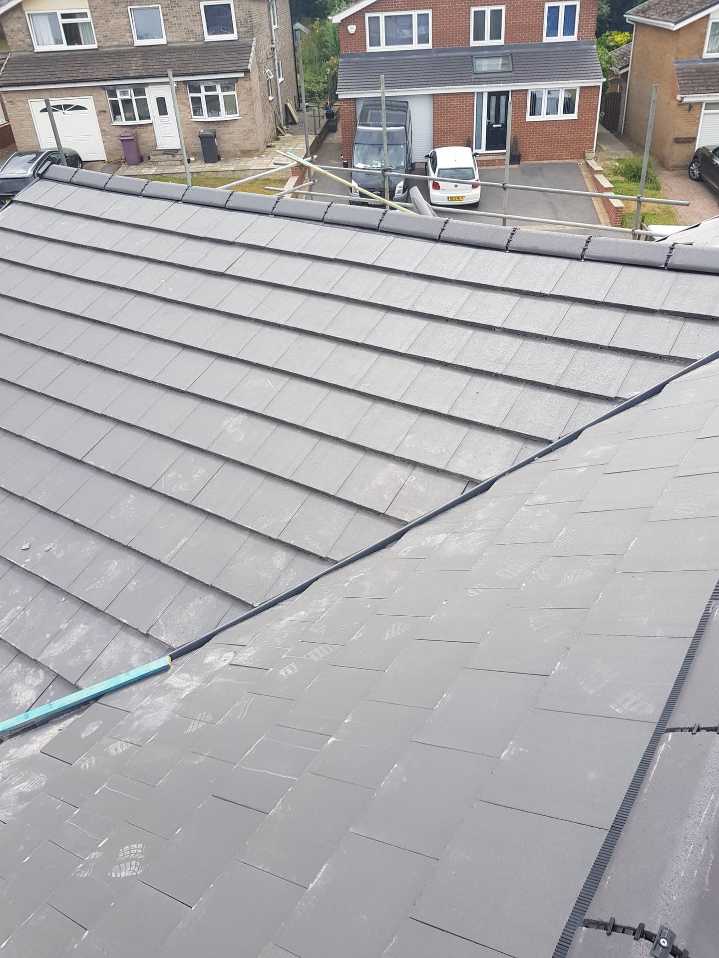 Newly completed grey slate pitched roof with ridge tiles on residential property