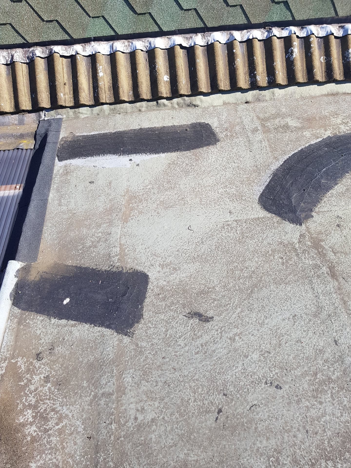 Flat roof with patches of repair work and corrugated edge detail