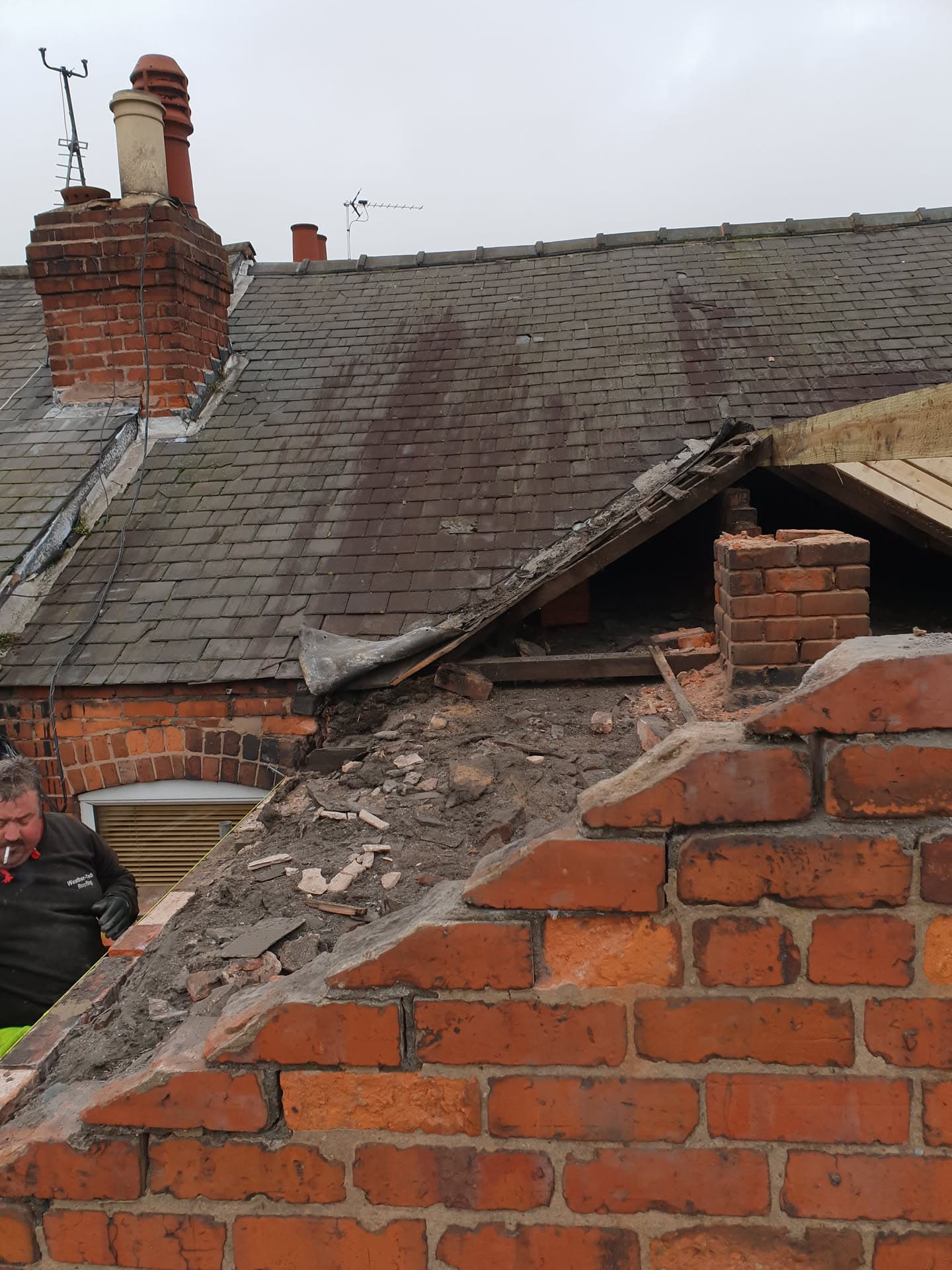 Pitched roof with concrete tiles and brick chimney stack showing structural damage requiring repair
