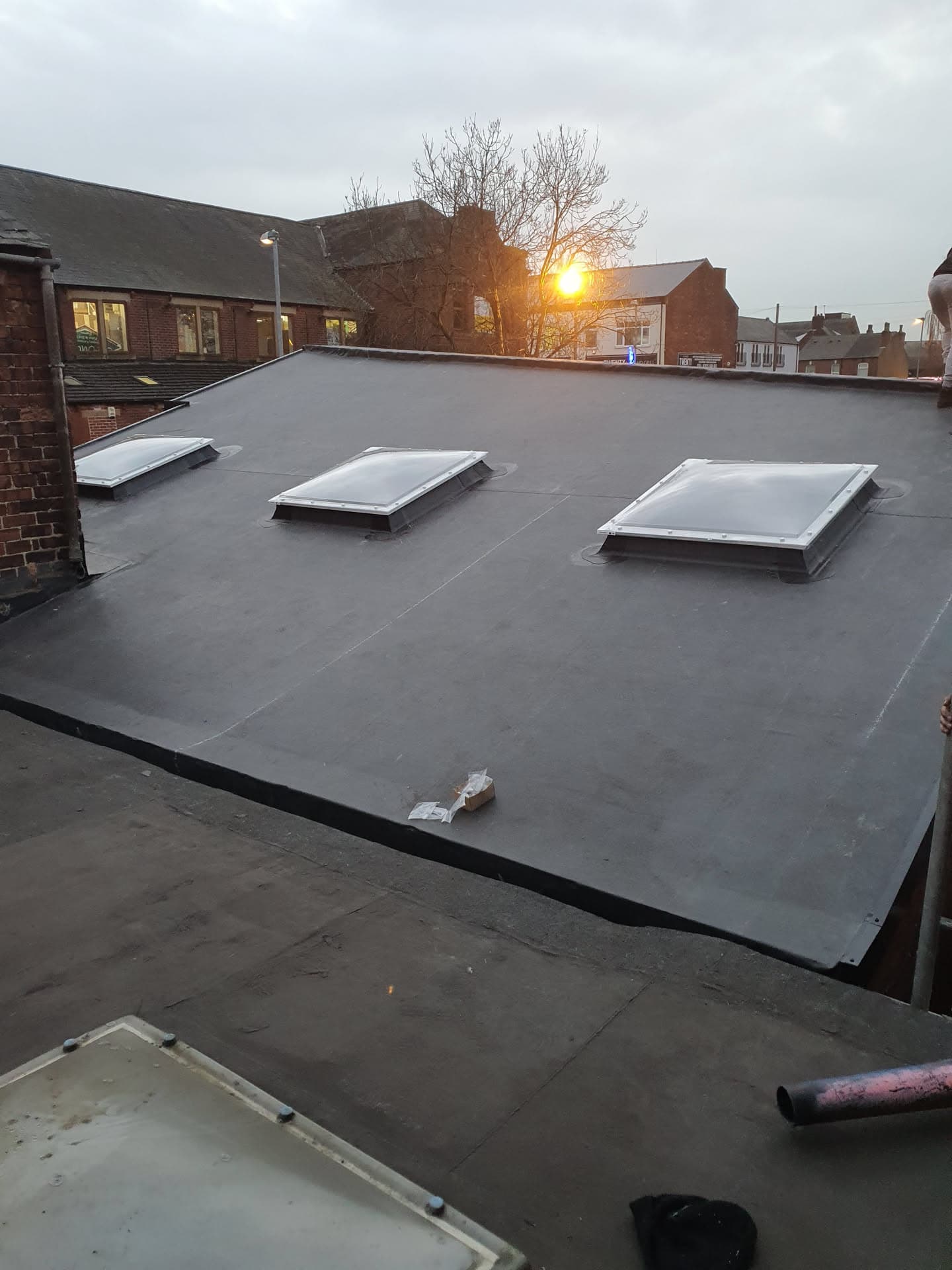 Flat roof with grey EPDM rubber membrane and three roof lights installed
