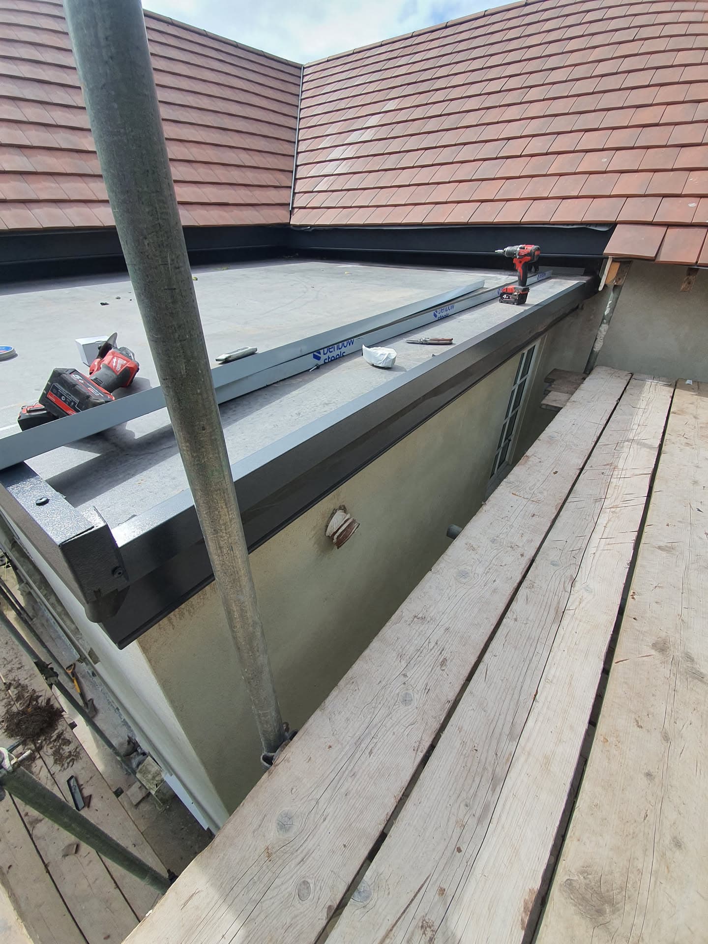 Flat roof extension with GRP fibreglass surface and terracotta tiled pitched roof above