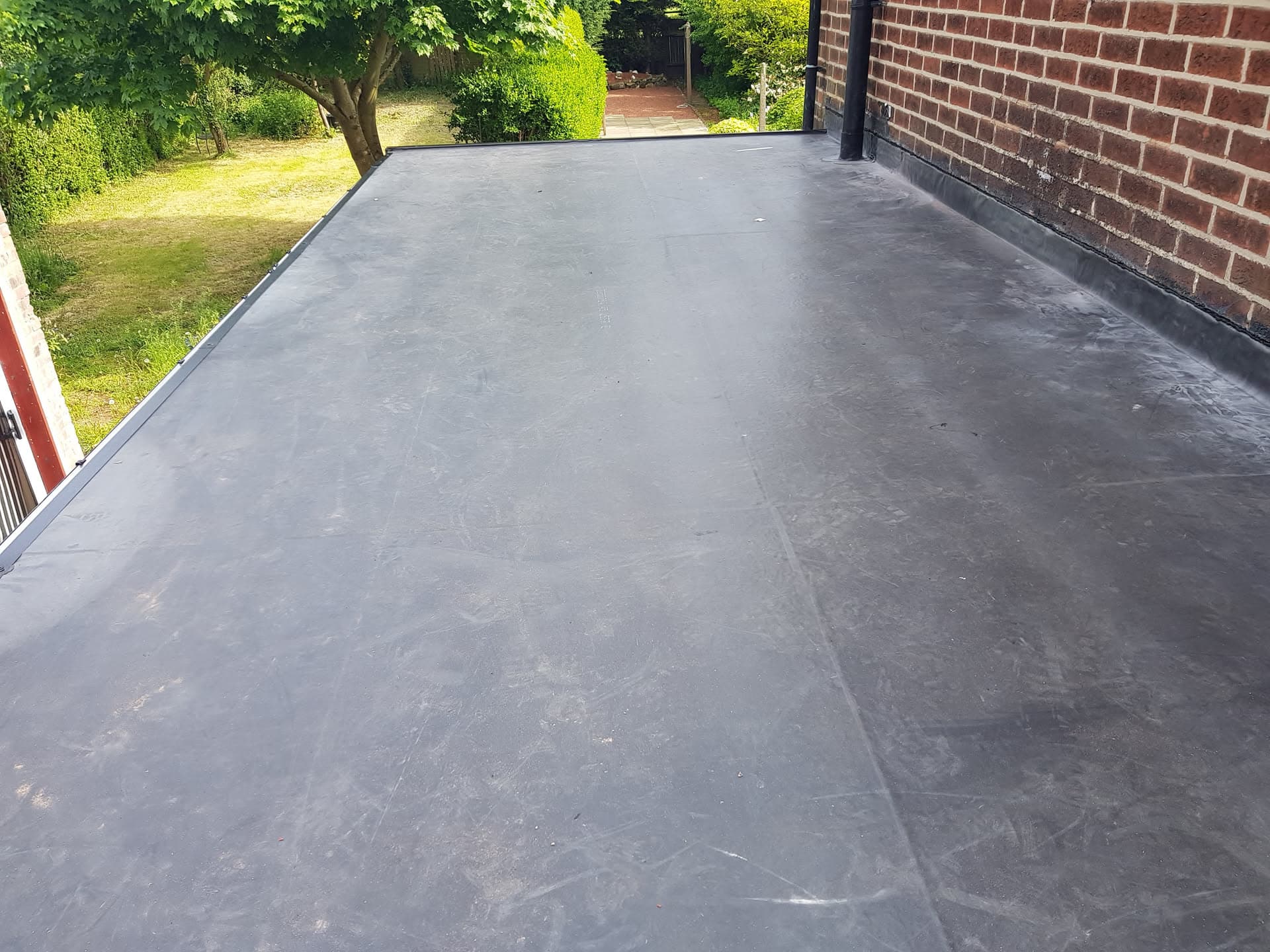Completed flat roof with grey EPDM rubber membrane on single-storey extension