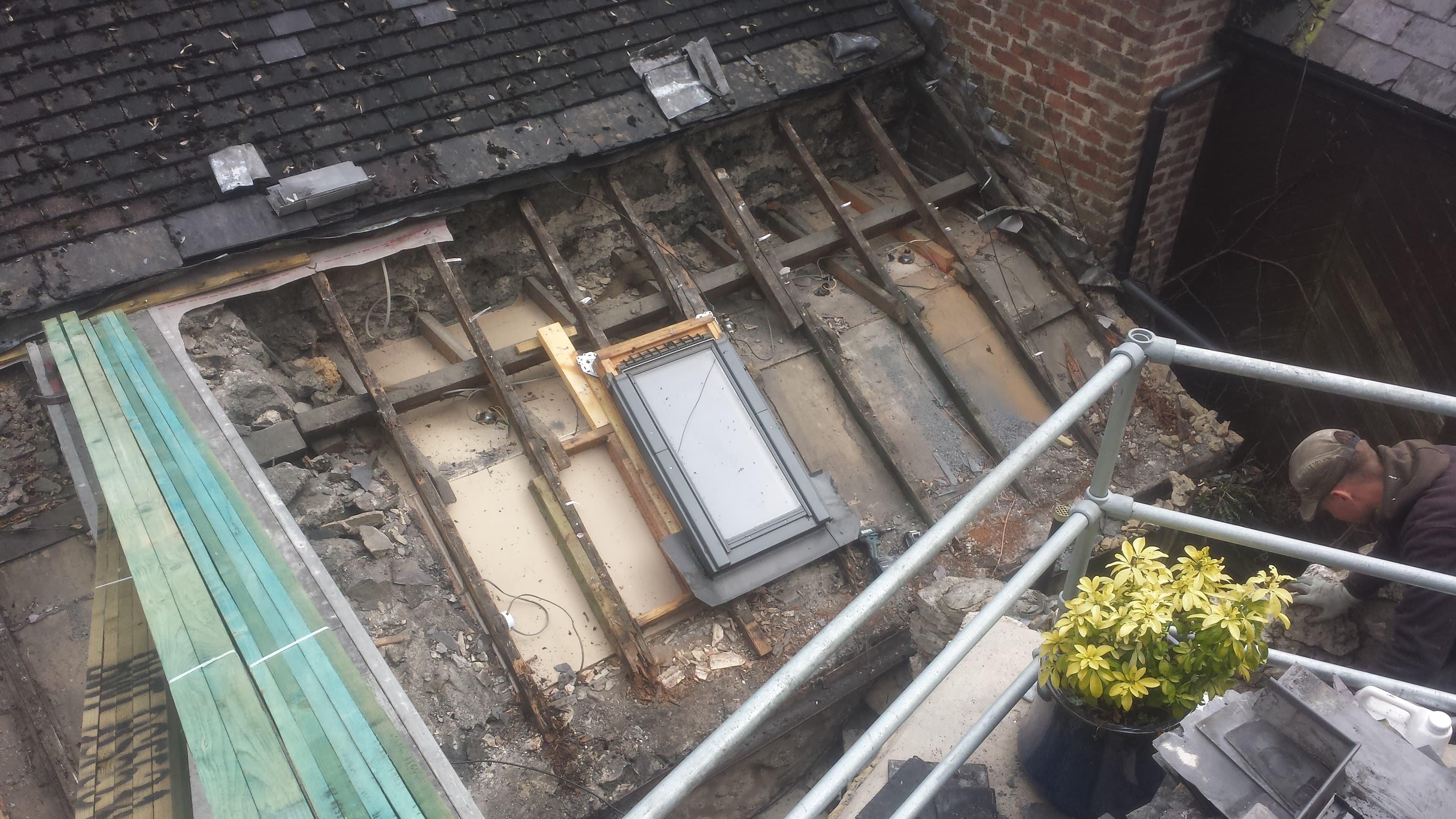 Flat roof stripped back to timber joists with skylight window and brick chimney stack