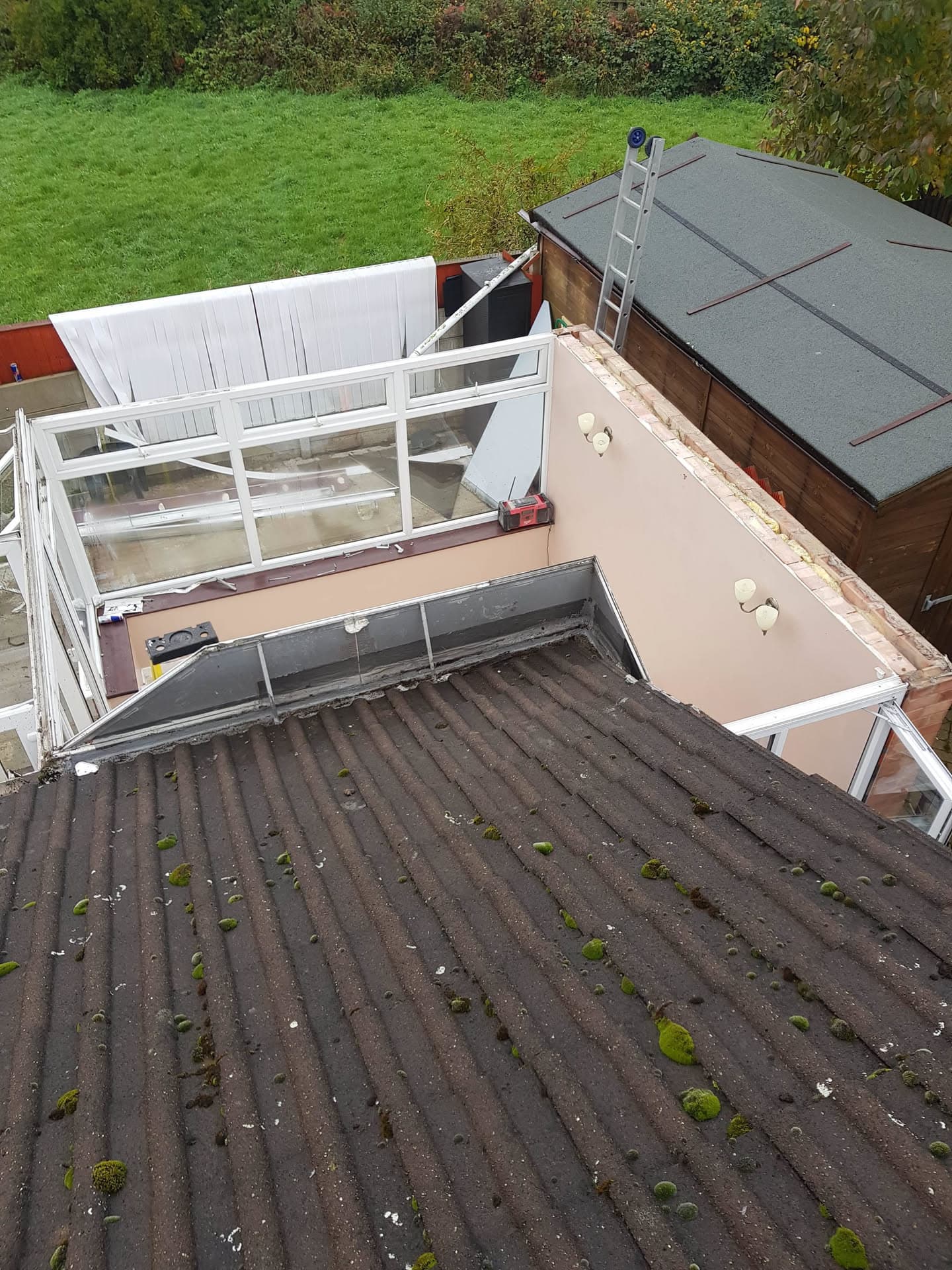 Aerial view of mossy corrugated roof with conservatory and flat roof extension
