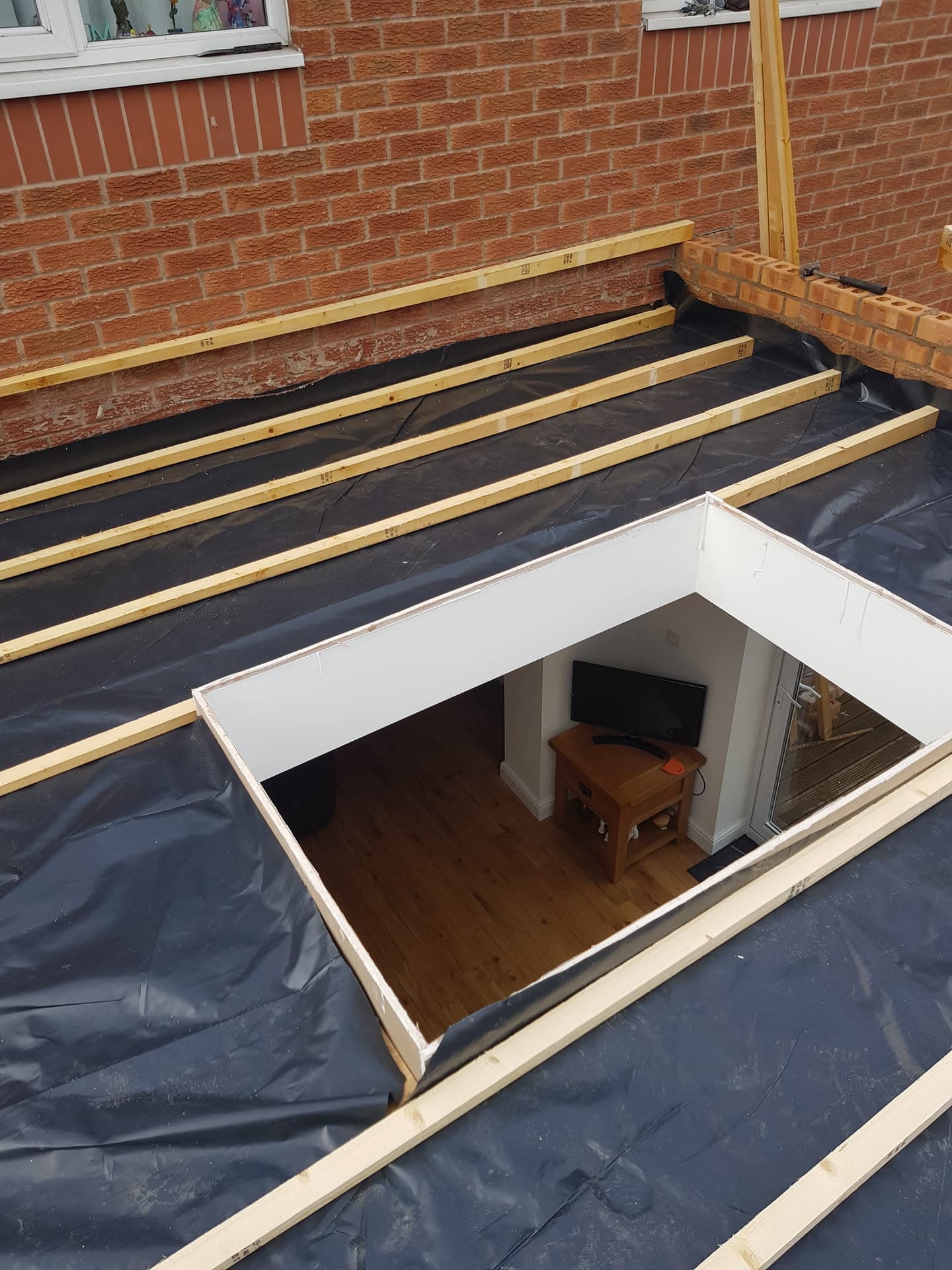 Flat roof construction with timber joists and black EPDM membrane around skylight opening