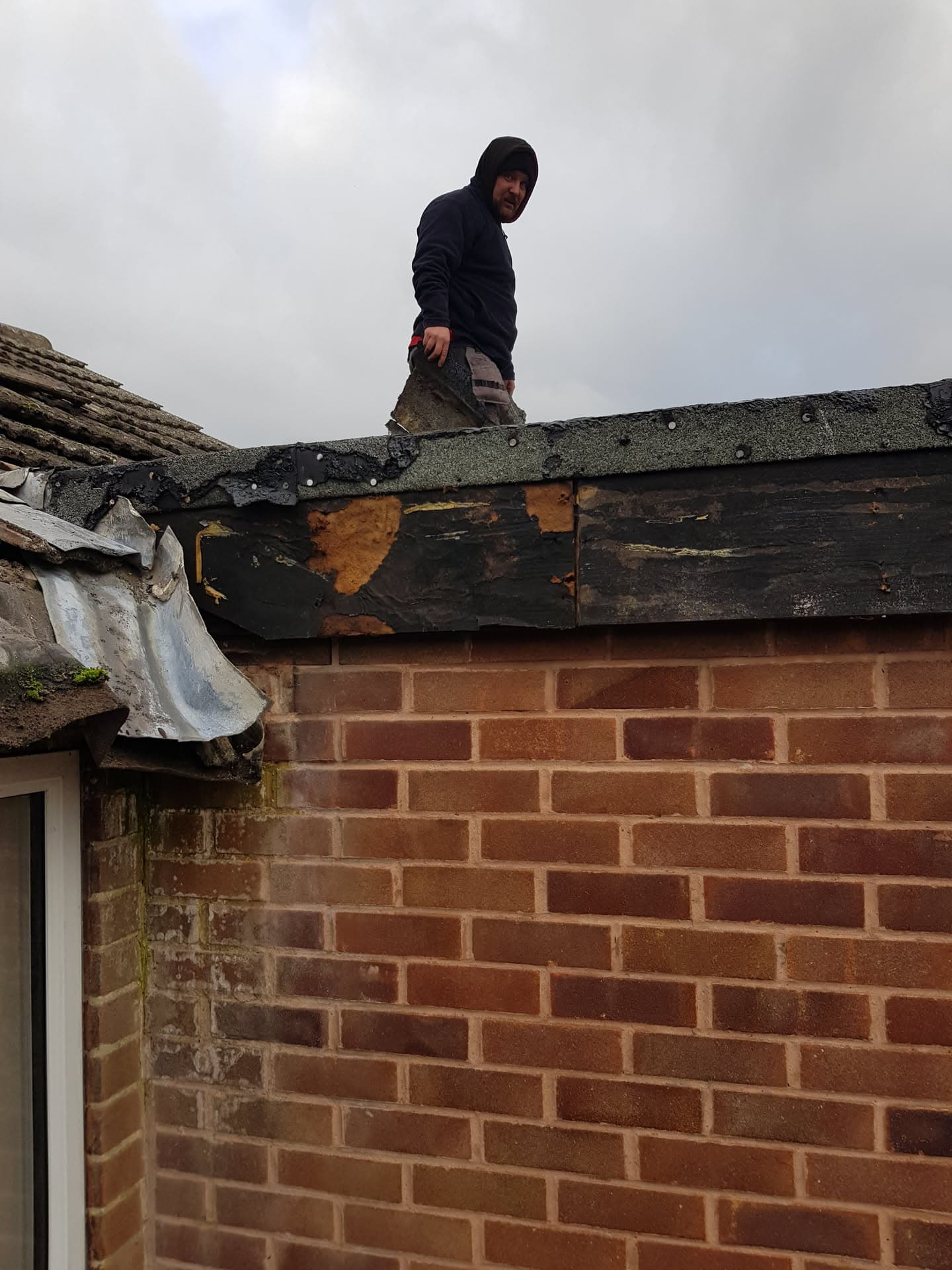 Roofer working on damaged fascia and soffit on pitched tiled roof