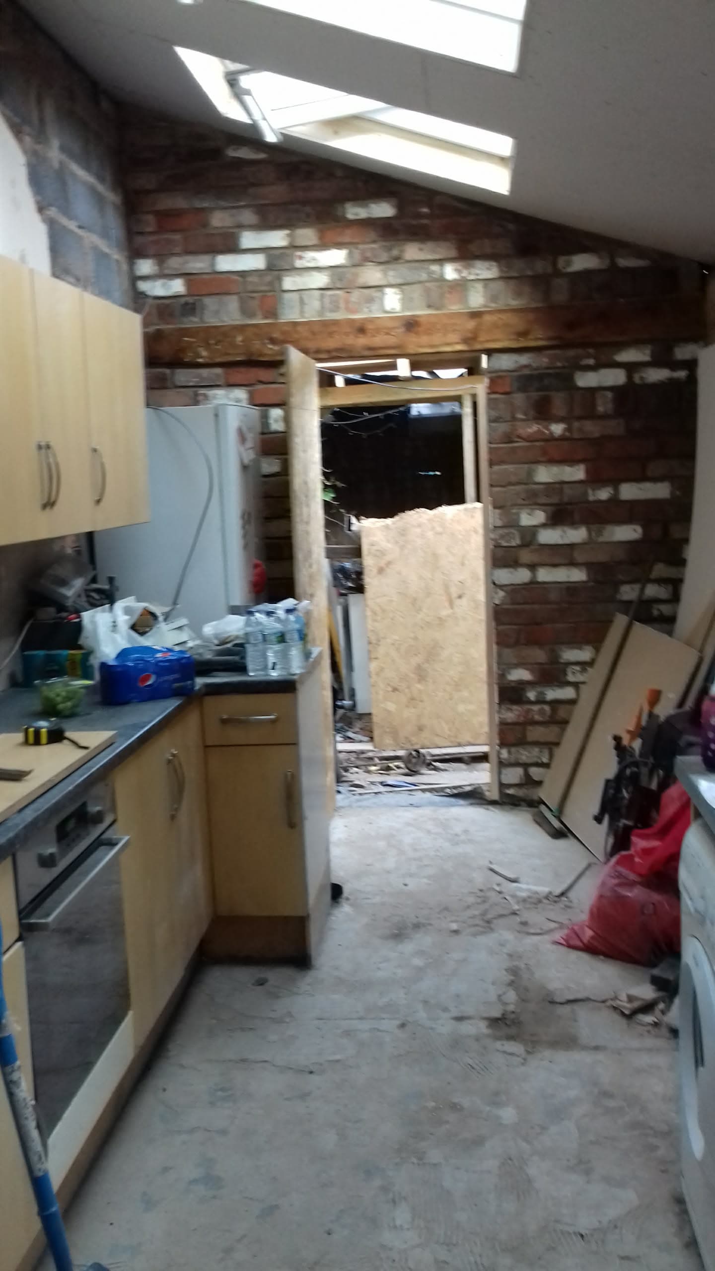 Interior kitchen extension with exposed brick wall and roof windows during renovation work