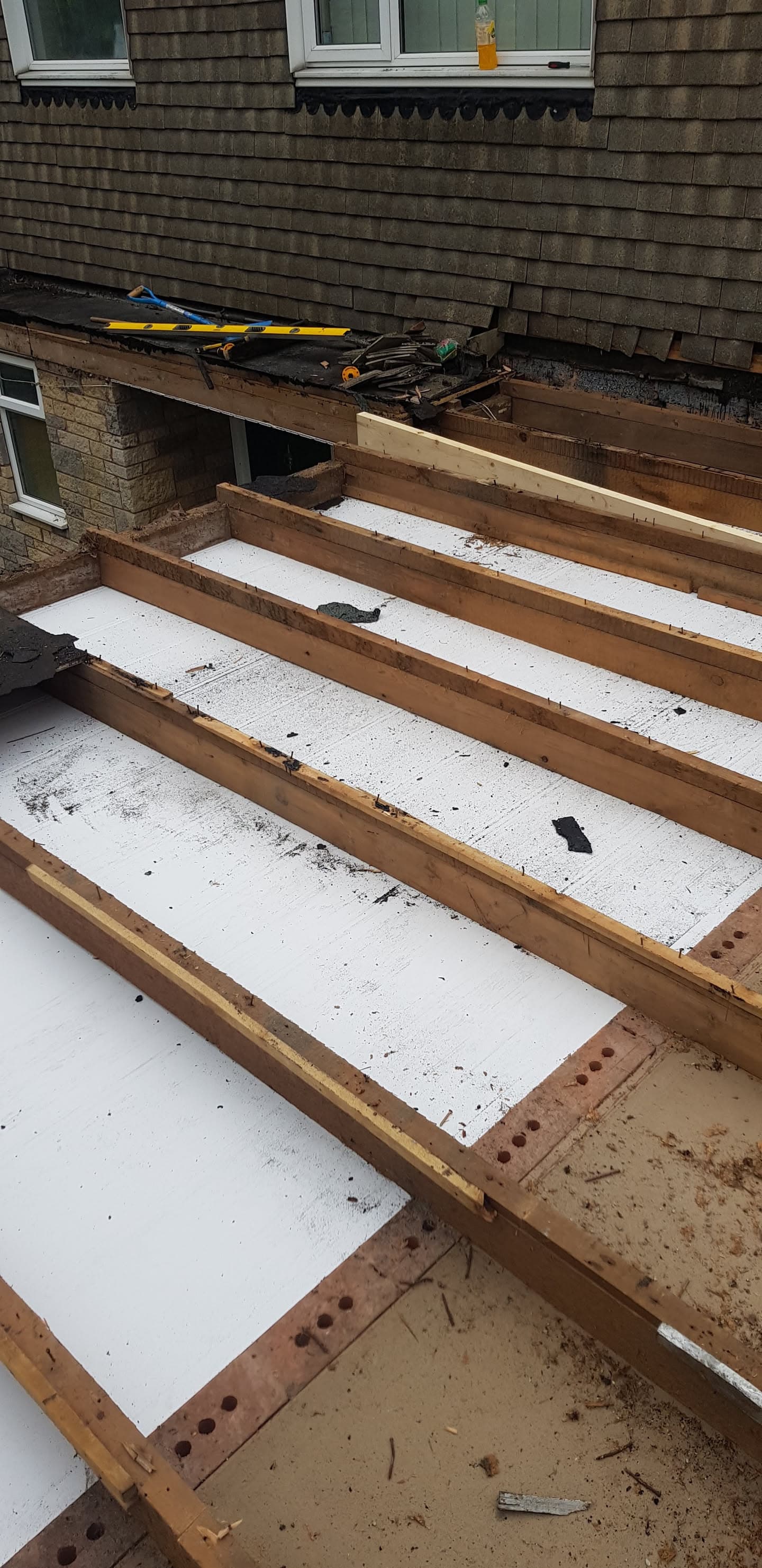 Flat roof construction showing timber joists with white insulation boards fitted between