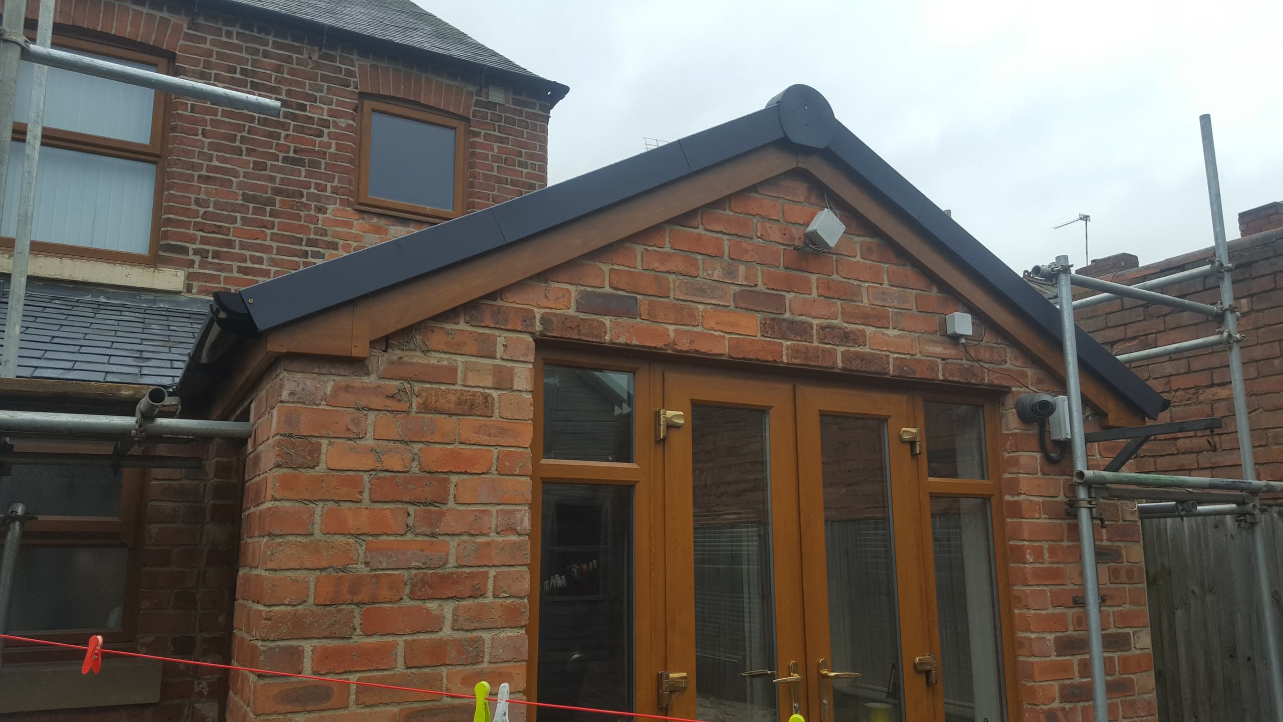 Pitched roof extension with dark grey ridge and fascias on red brick structure