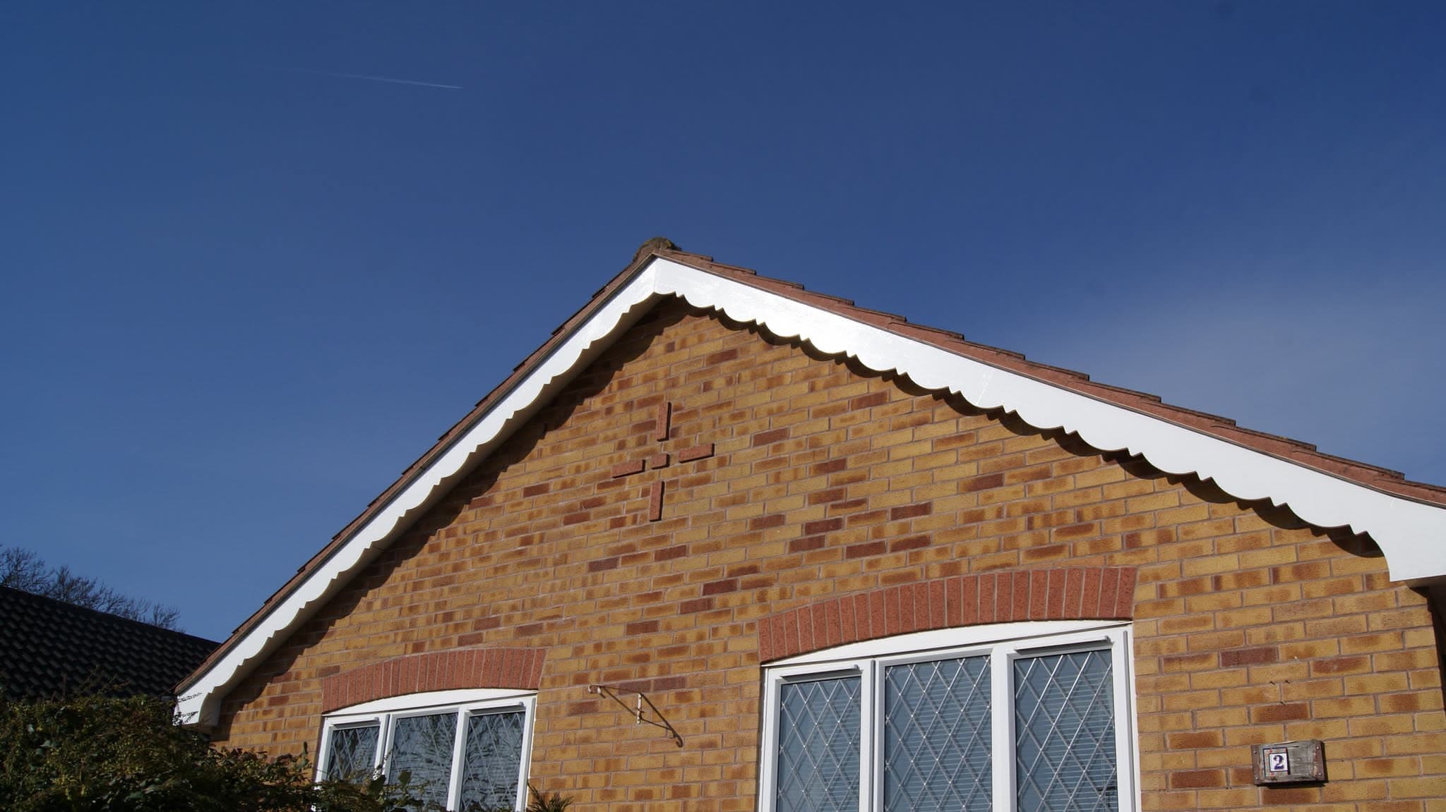 Pitched roof with terracotta clay tiles and white fascias on brick gable end