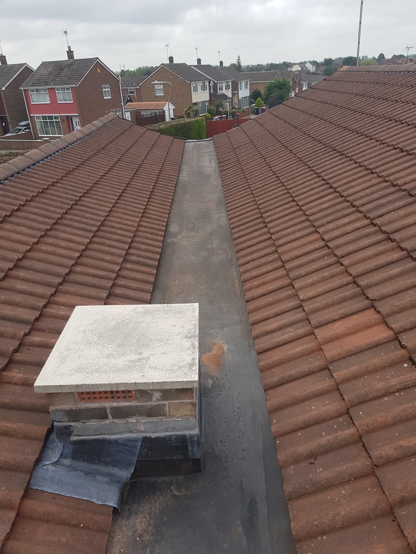 Pitched roof with terracotta concrete tiles, lead valley gutter and chimney with lead flashing